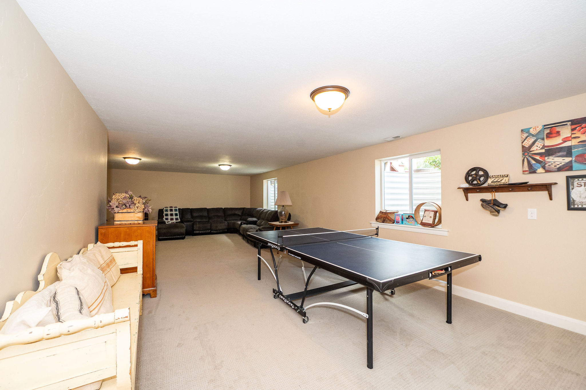 Spacious lower-level room featuring light-toned walls and carpet flooring