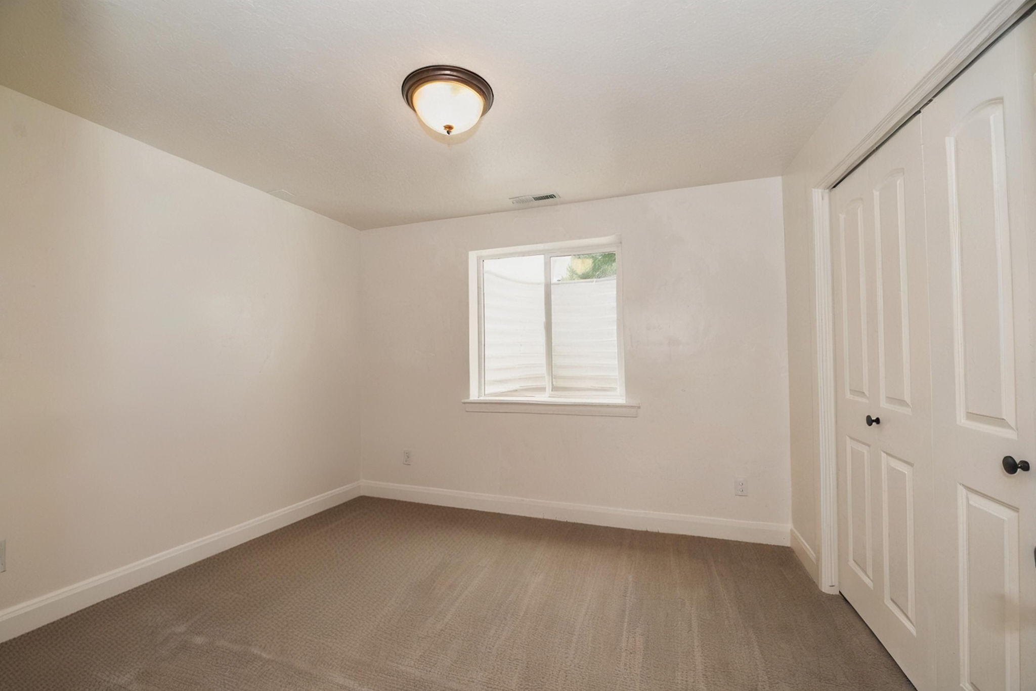 Carpeted room featuring a white-trimmed window, white baseboards, and a bronze-finish flush mount ceiling light