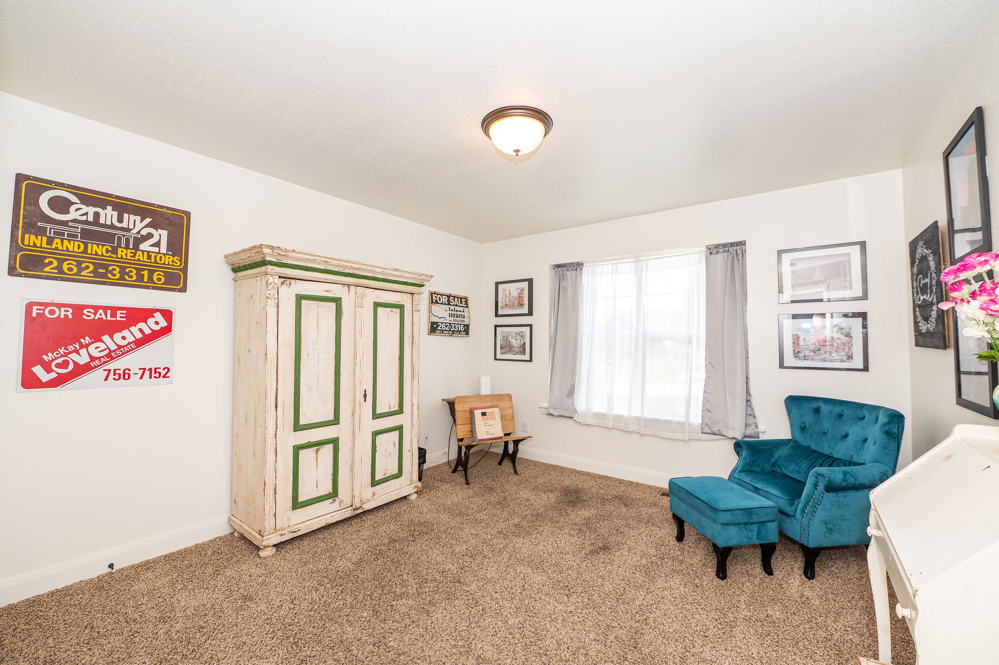 Carpeted interior space featuring a window with natural light, white walls, and a ceiling-mounted light fixture