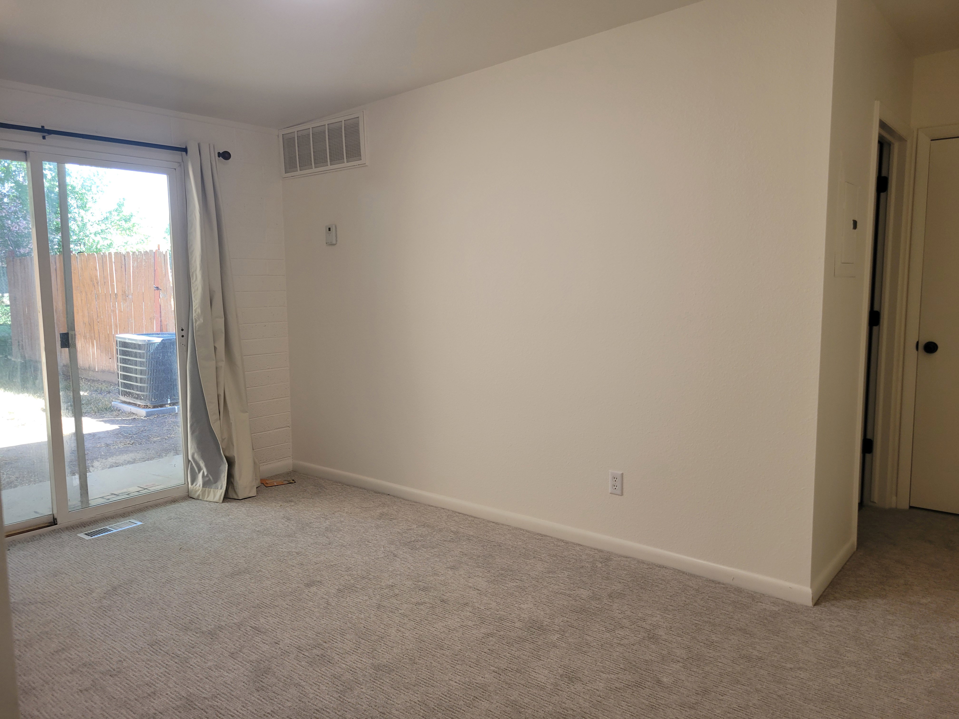 Main bedroom with fresh paint and new carpet with access to the rear patio and yard.