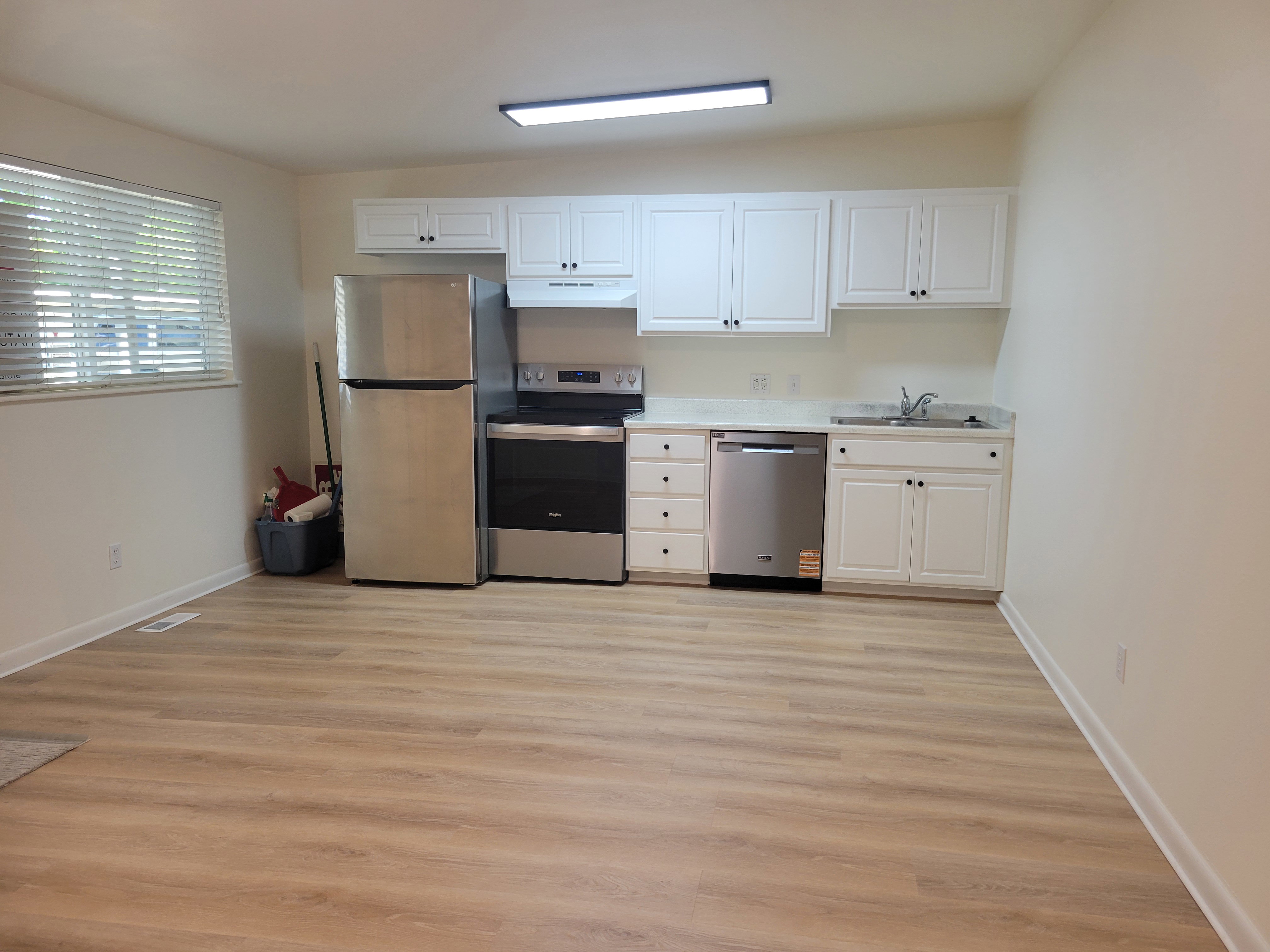 Another view of kitchen space featuring white cabinetry, light-toned countertops, stainless steel appliances and new LVP flooring.