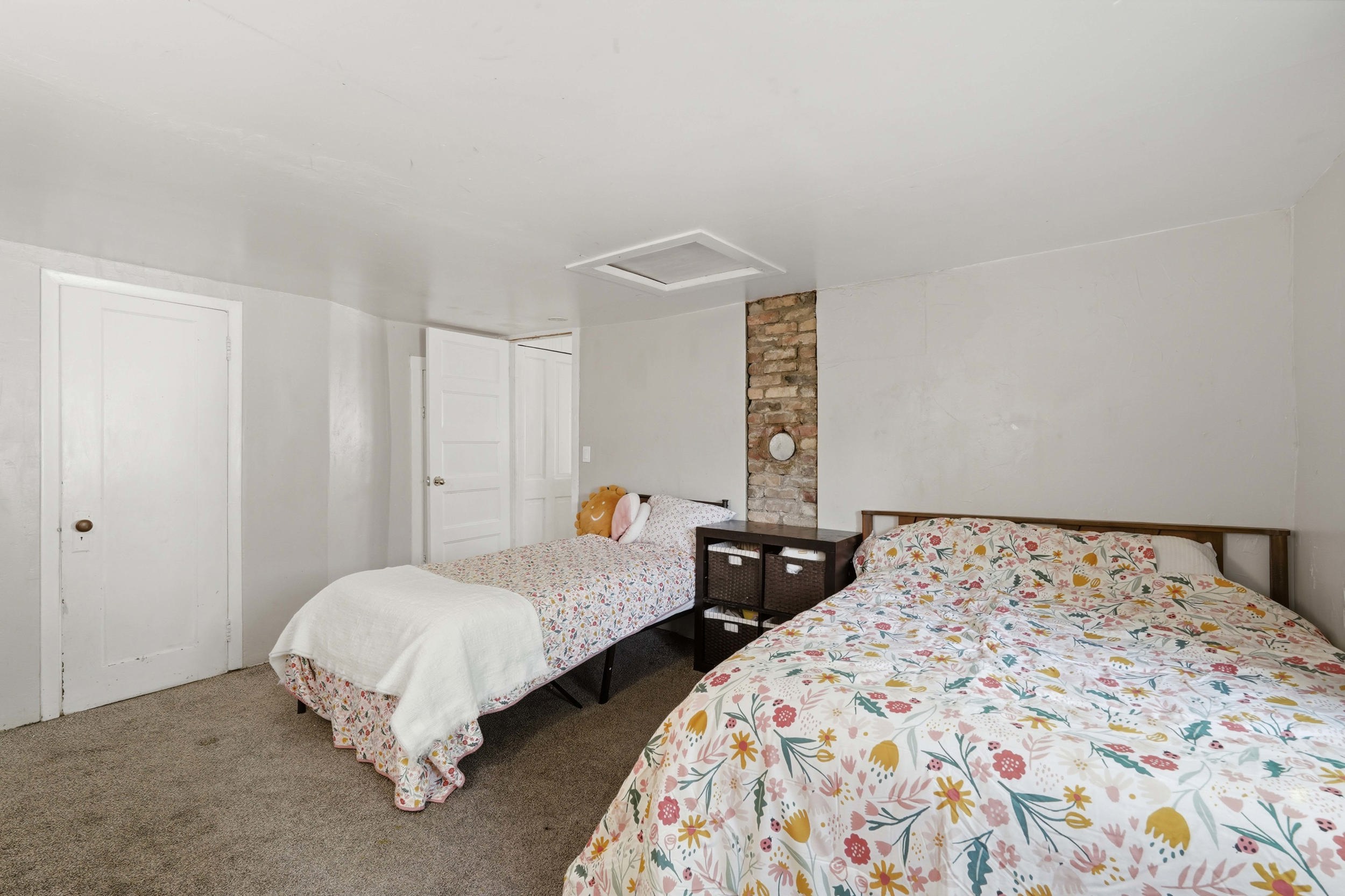 Bedroom #3, interior space featuring an exposed brick accent, white painted walls, and white paneled door (closed door is where powder bath is located).
