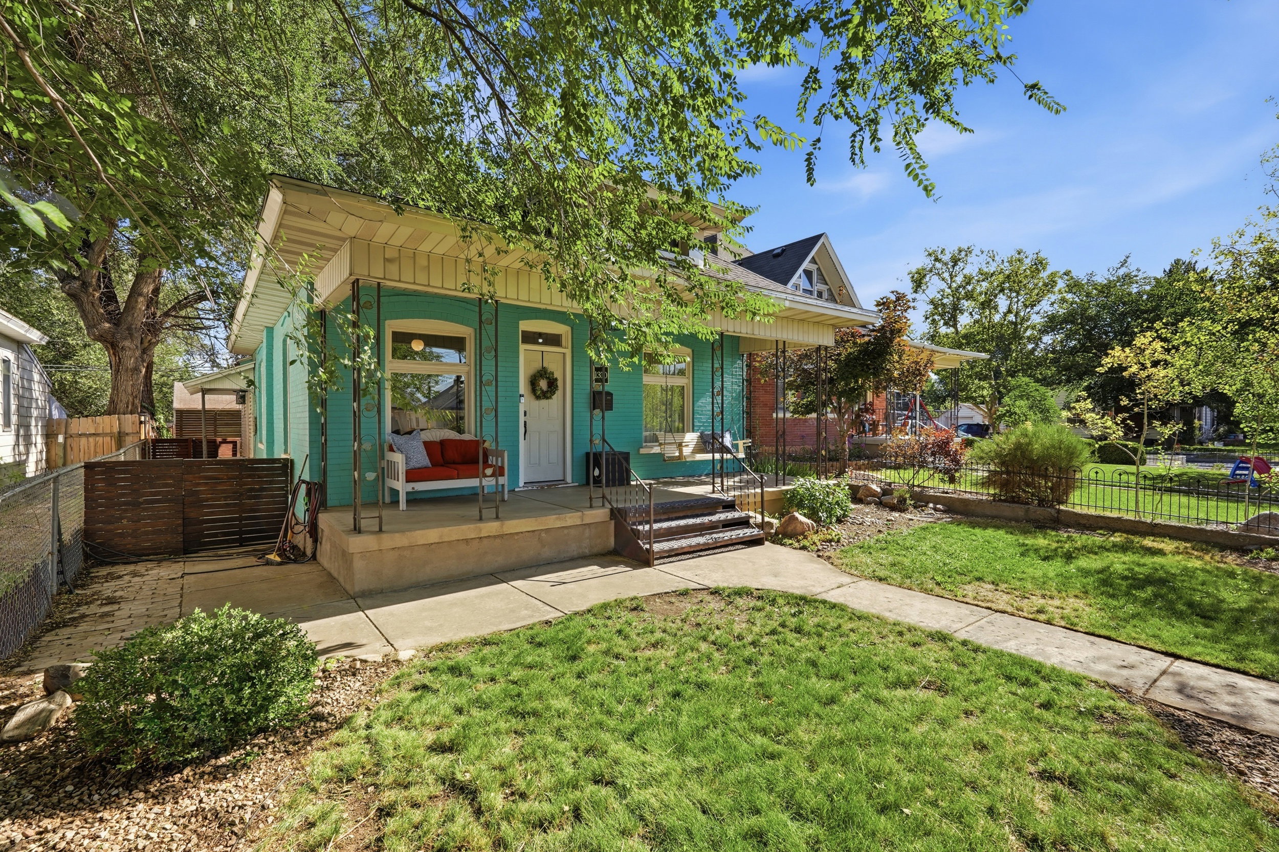 Turquoise exterior with white trim and a covered front porch featuring decorative metal posts