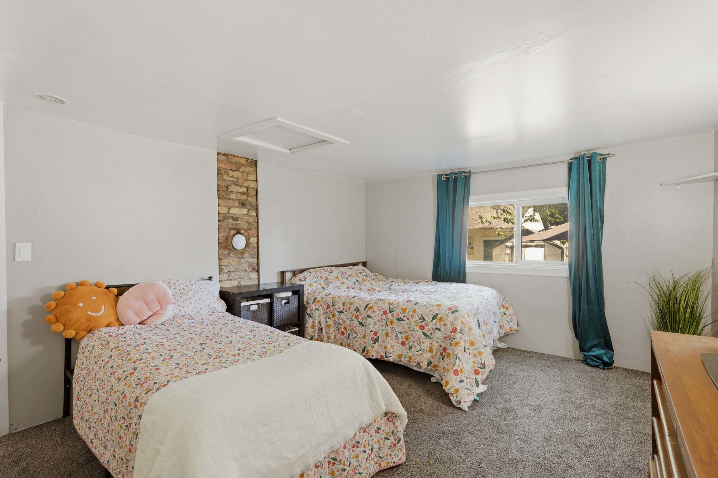 Bedroom #3, featuring an exposed brick accent, a white ceiling with an attic access panel, and grey carpeting