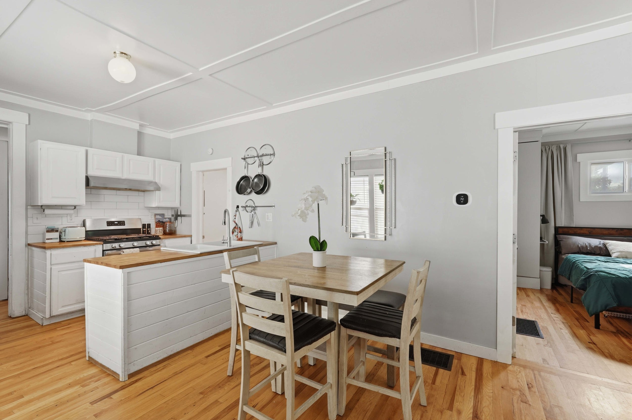 Bright kitchen featuring white cabinetry, wood-finish countertops, stainless steel appliances, and a subway tile backsplash
