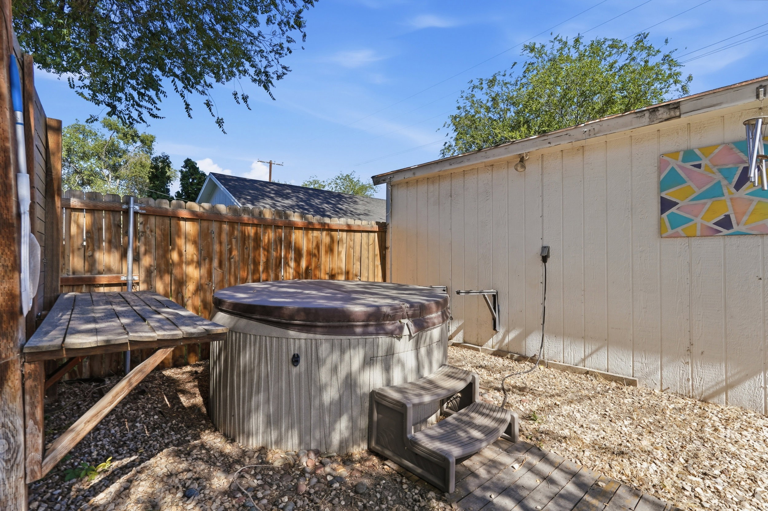 Outdoor spa with a protective cover and integrated steps, surrounded by a gravel ground cover. Can be included.