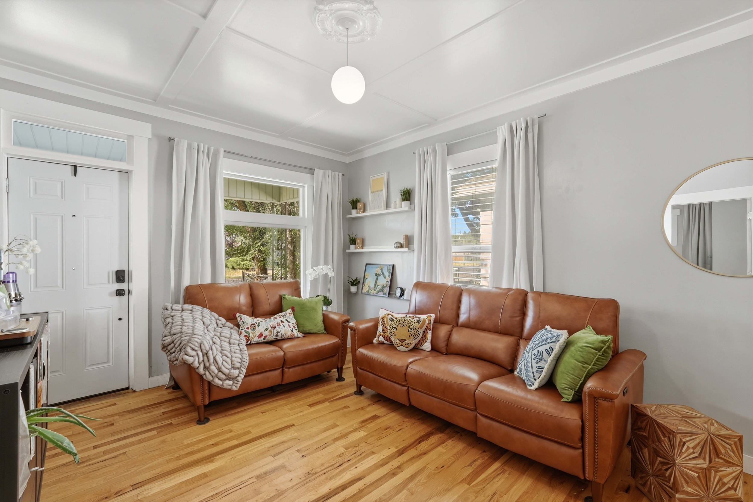 Living area featuring wood-finish flooring, two large windows with white trim, and light gray wall paint