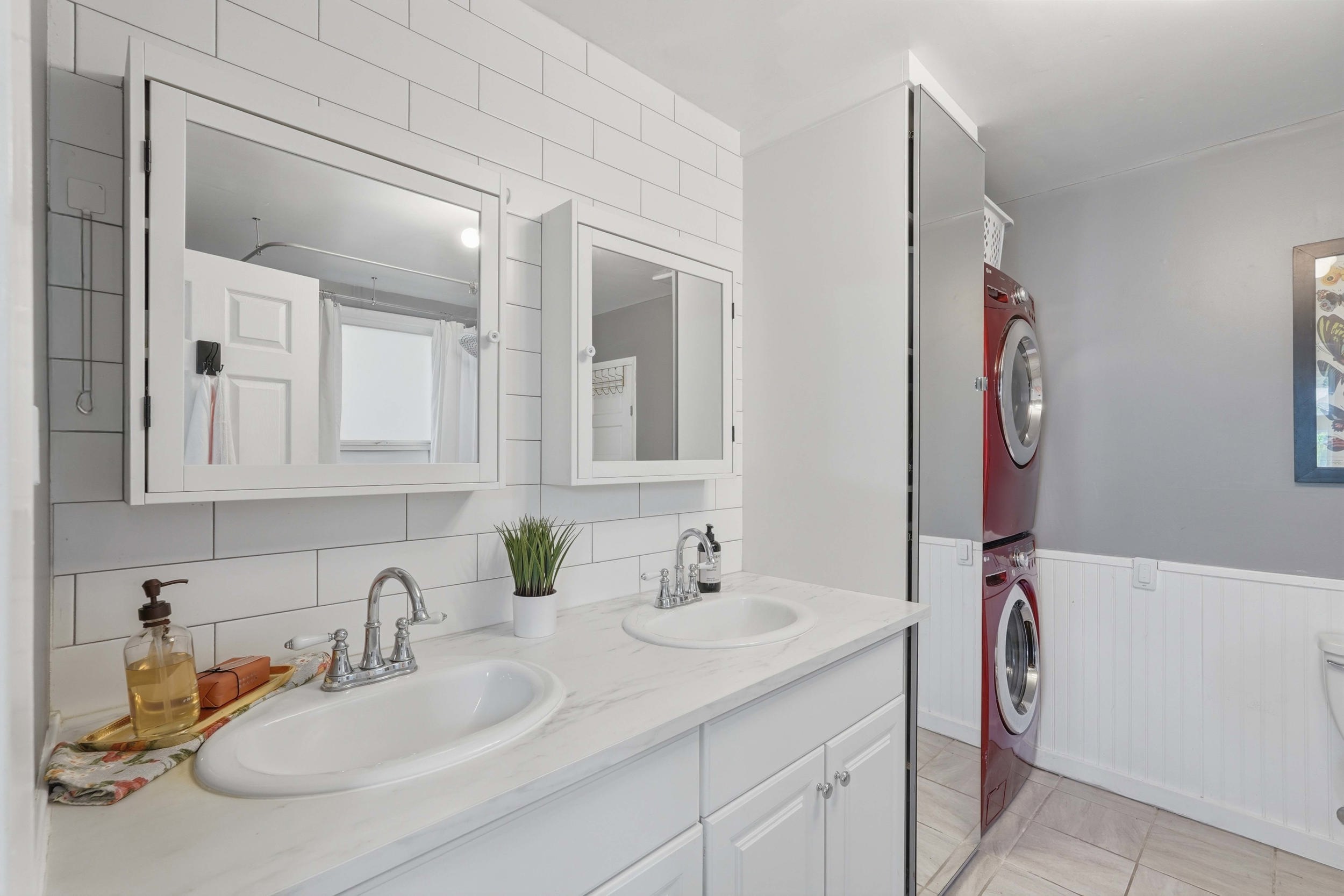 Owners suite, Dual vanity with integrated sinks, white cabinetry, and wall-mounted mirrored medicine cabinets