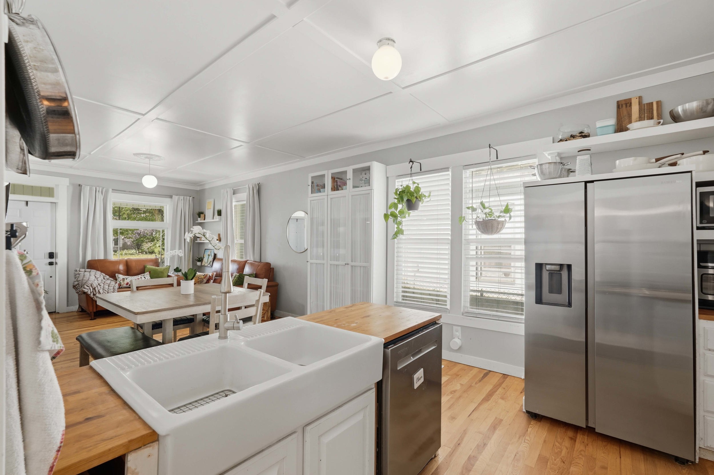 Kitchen featuring a double basin farmhouse sink, wood butcher block countertops, stainless steel appliances, and wood-finish flooring