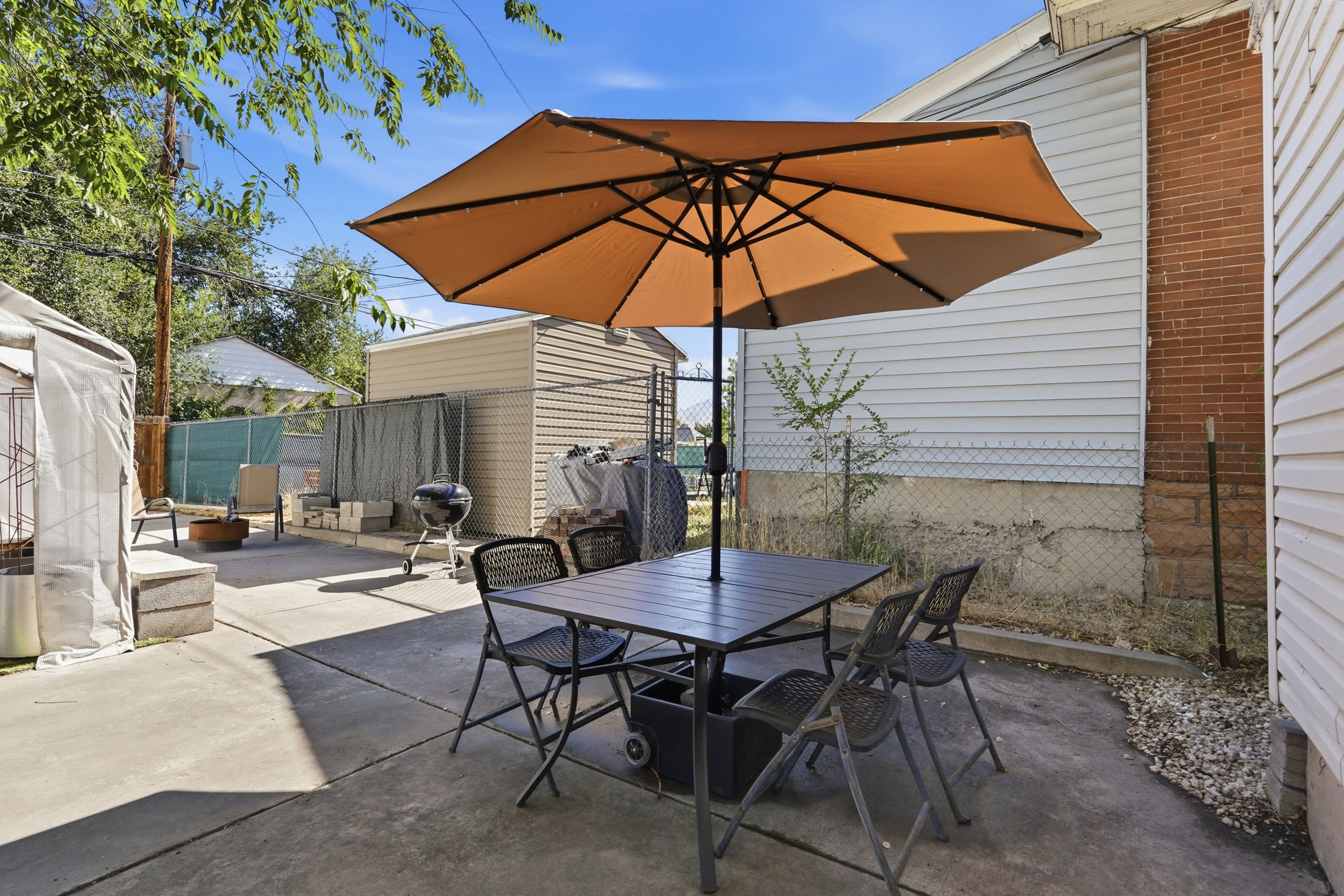 Paved patio area featuring a free-standing umbrella, concrete surfacing, and a visible outbuilding