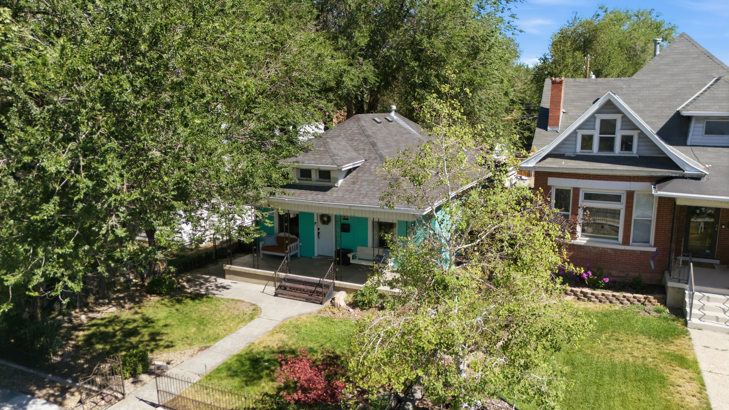 Charming single-story residence featuring a covered front porch, light blue exterior siding, and a dark shingle roof