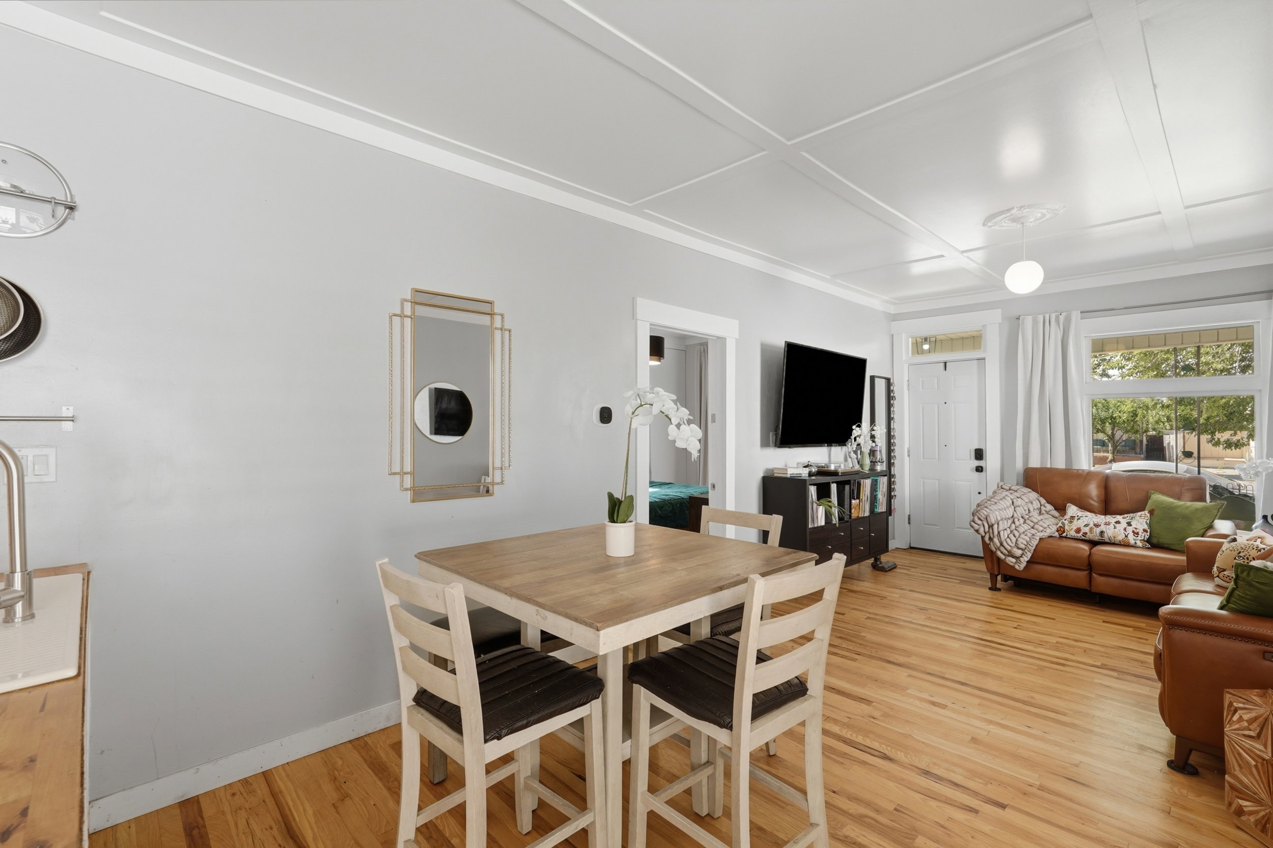 Open-concept living space with light wood-finish flooring, a coffered ceiling, and crown molding