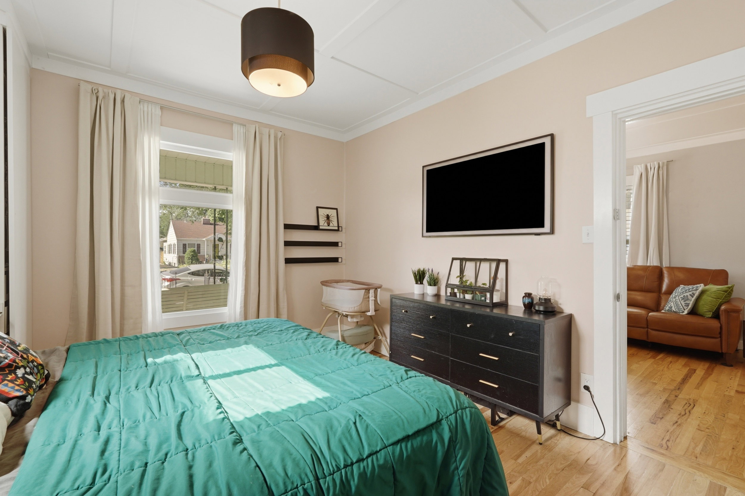 Natural light illuminates a room featuring light-colored walls and a drum pendant light fixture. Owners suite.