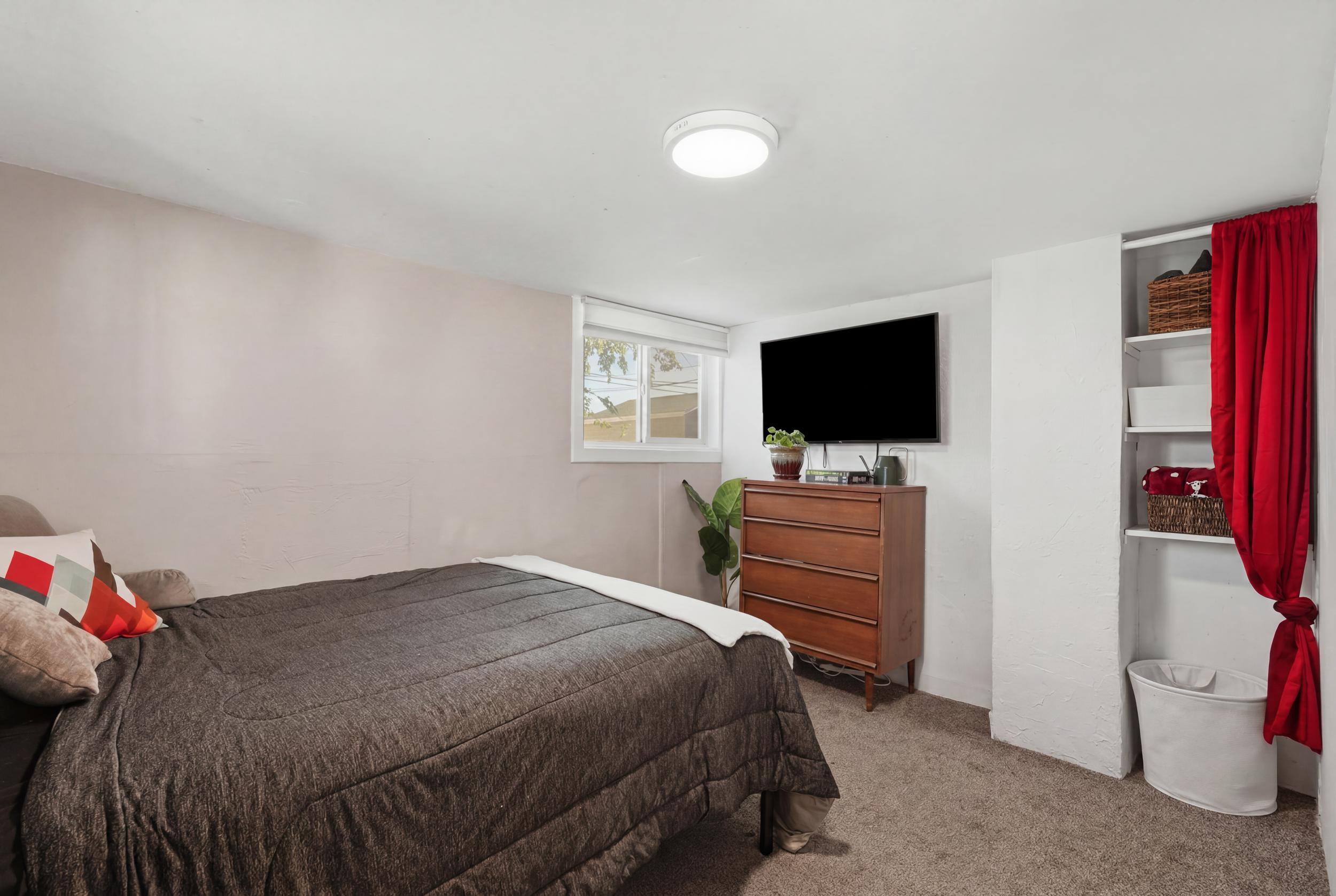 Bedroom #2 featuring light-colored walls, window with blinds, overhead flush mount lighting, and built-in shelving
