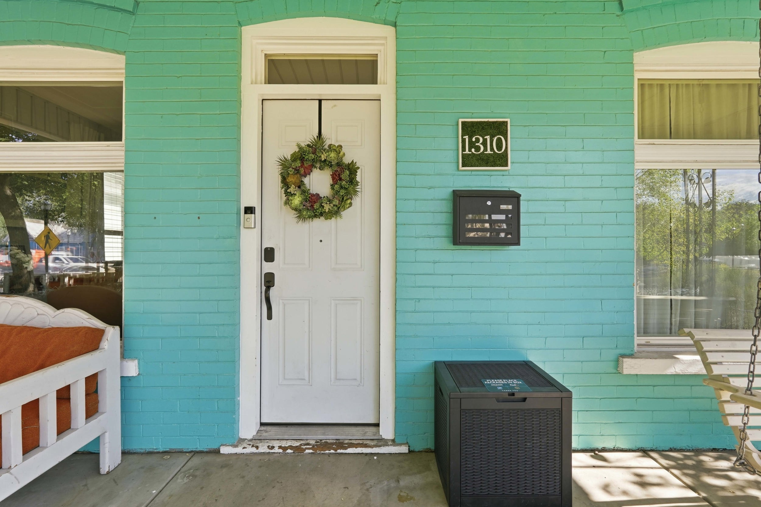 Inviting front entrance featuring a white door with transom window, teal brick facade, and a modern wall-mounted mailbox