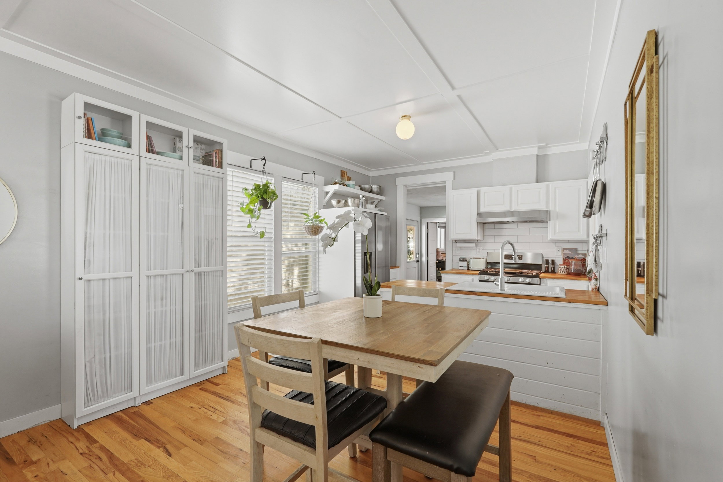 Eat-in kitchen featuring wood-finish flooring, white cabinetry, a subway tile backsplash, and a wood countertop
