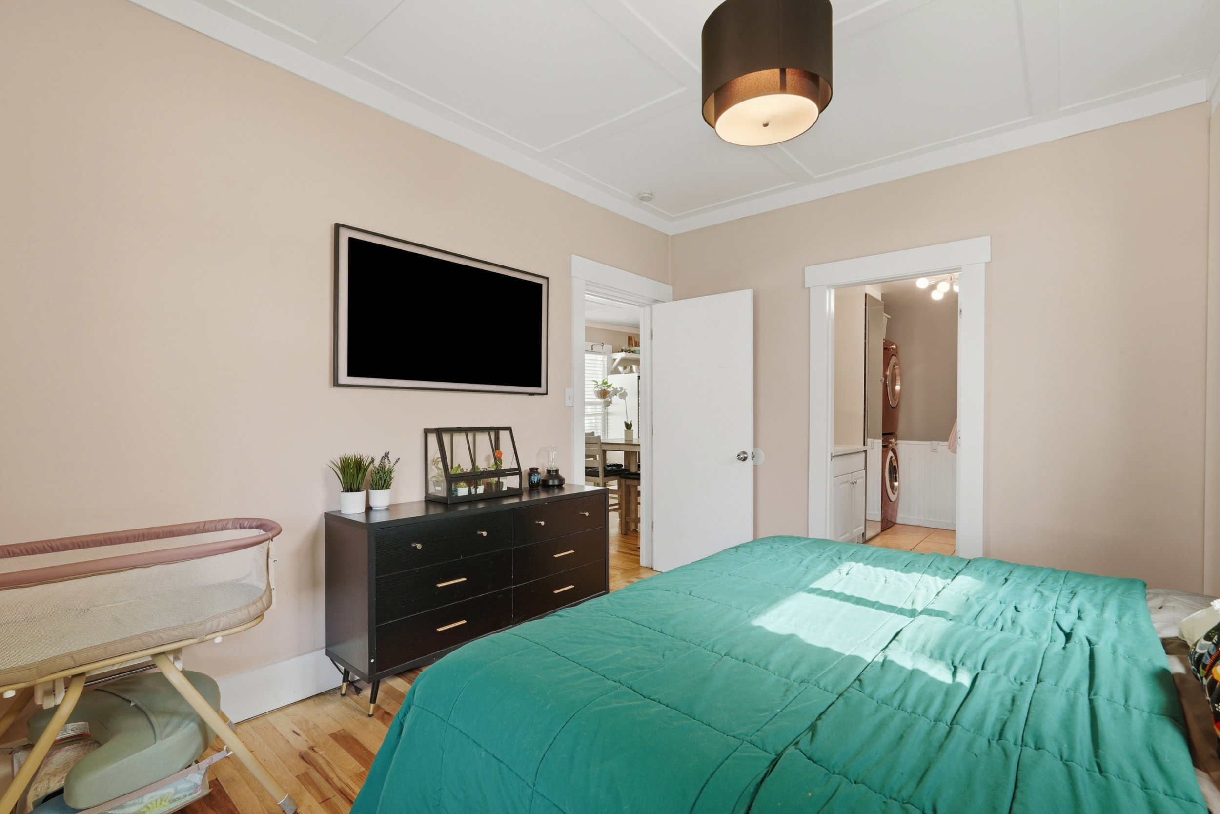 Owners suite featuring wood-finish flooring, crown molding, and a ceiling-mounted light fixture