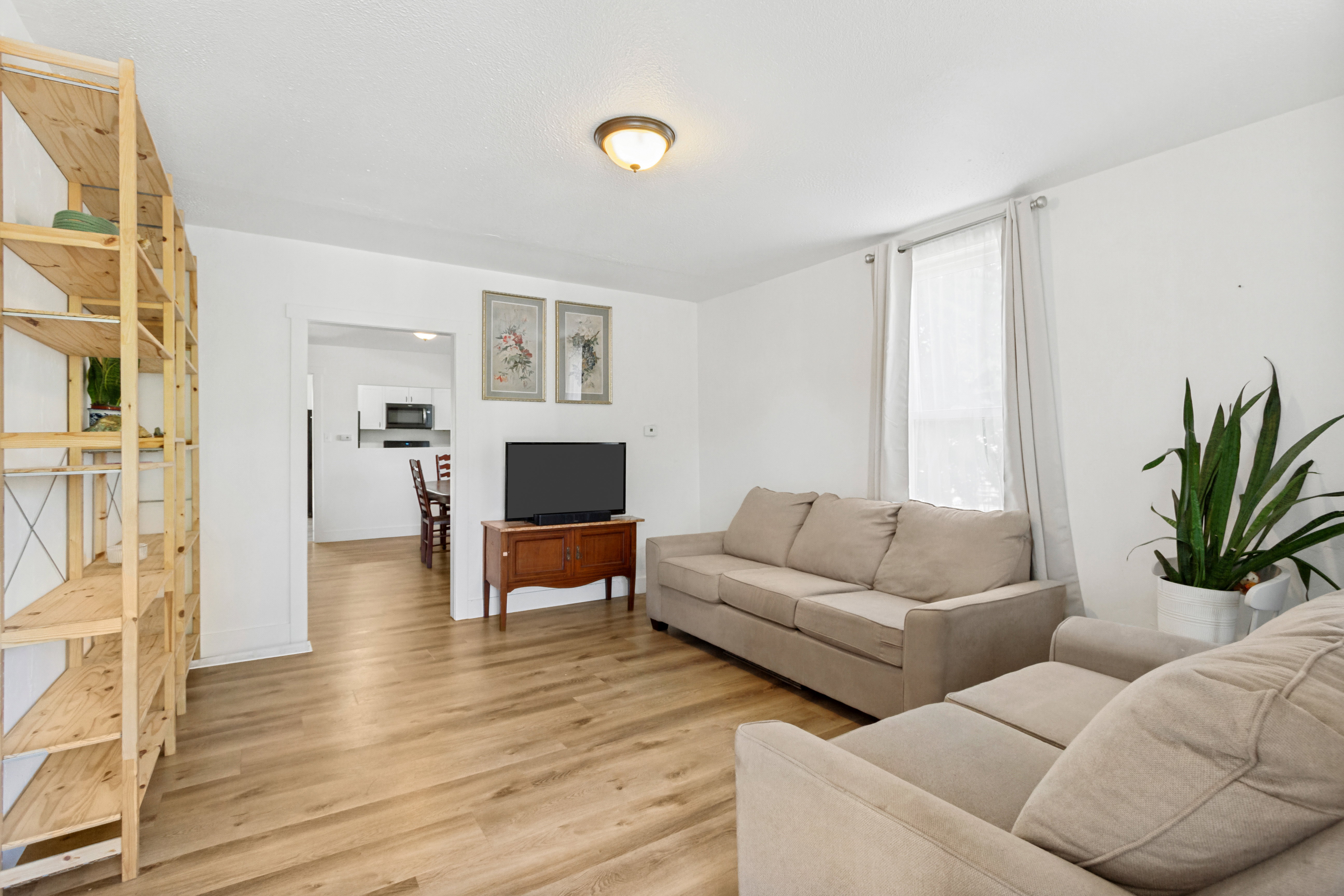 Open living area featuring laminate  flooring, white walls, a ceiling-mounted light fixture