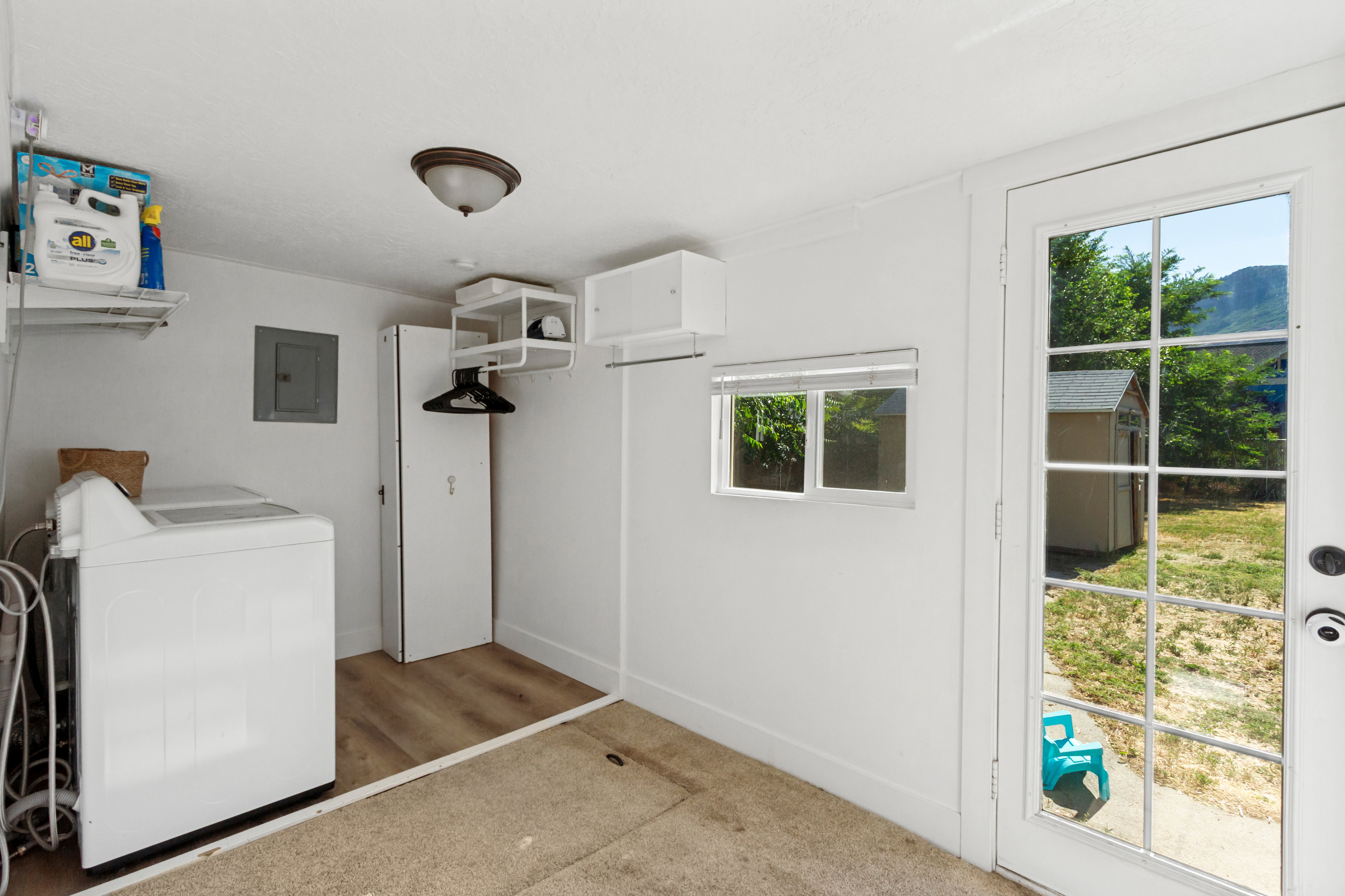 Utility room featuring a paneled glass door, a window with blinds, and built-in shelving