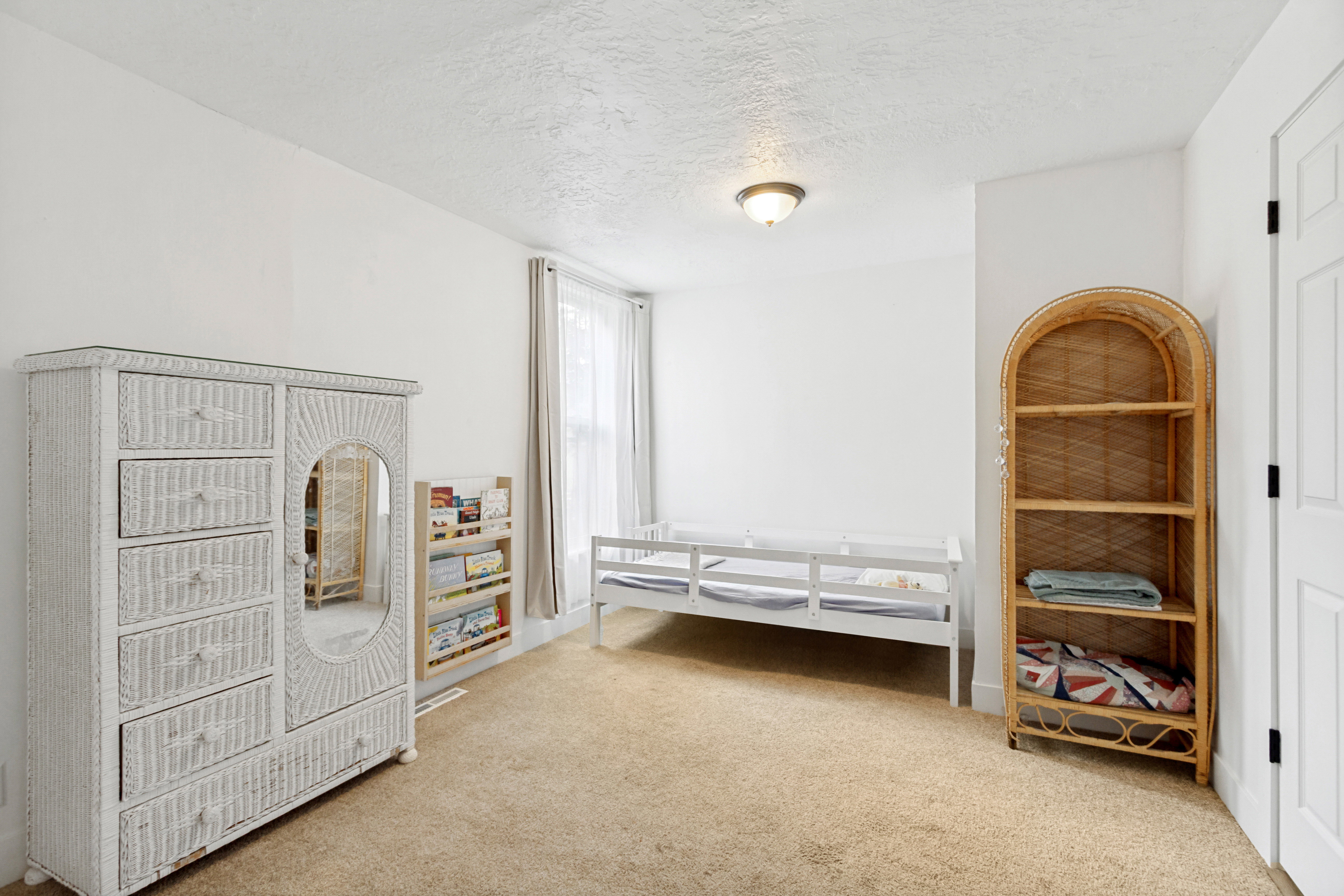 Carpeted room with white walls, a white door with black hardware, and an overhead flush-mount light fixture