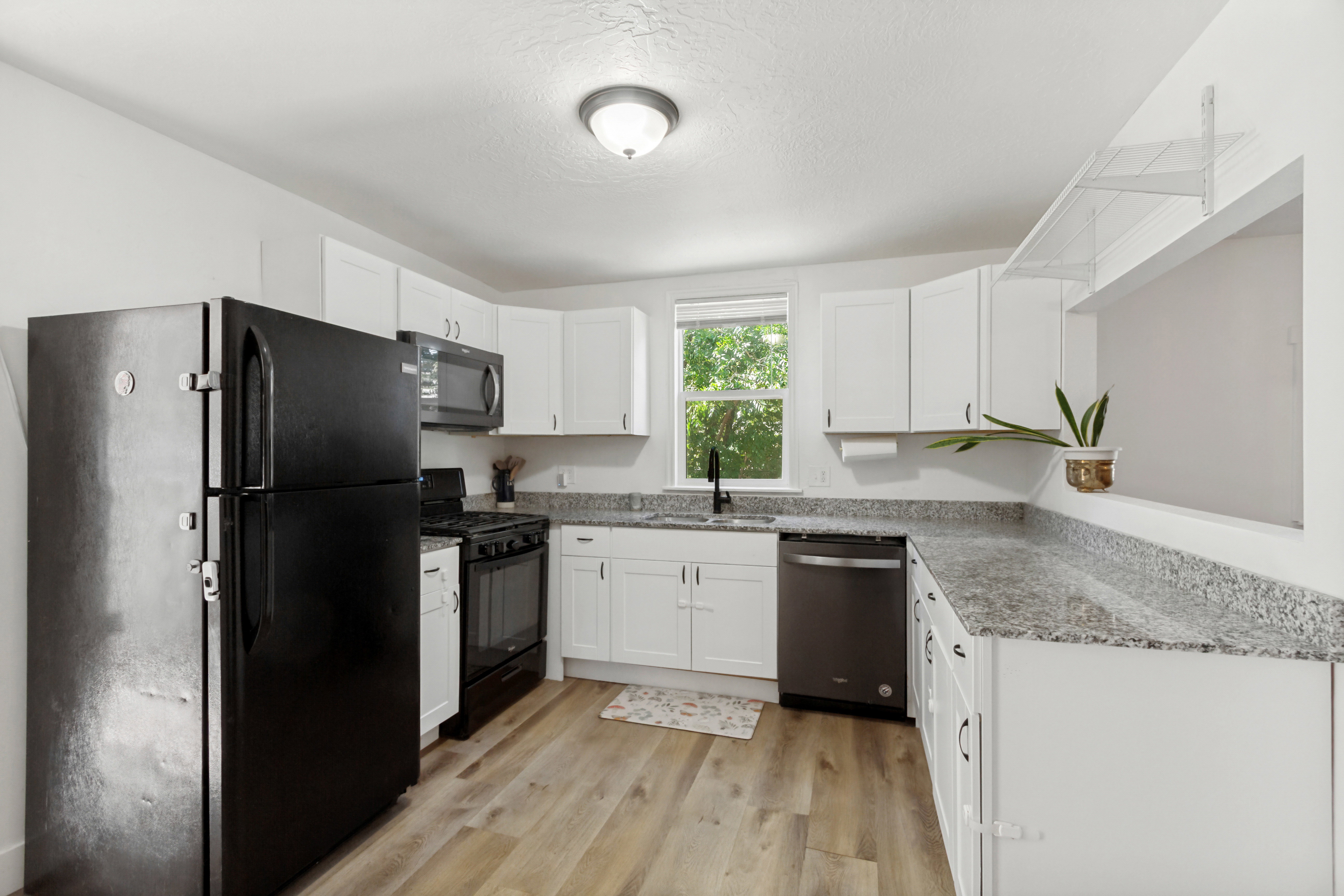 Modern kitchen featuring white cabinetry, laminate, and granite countertops