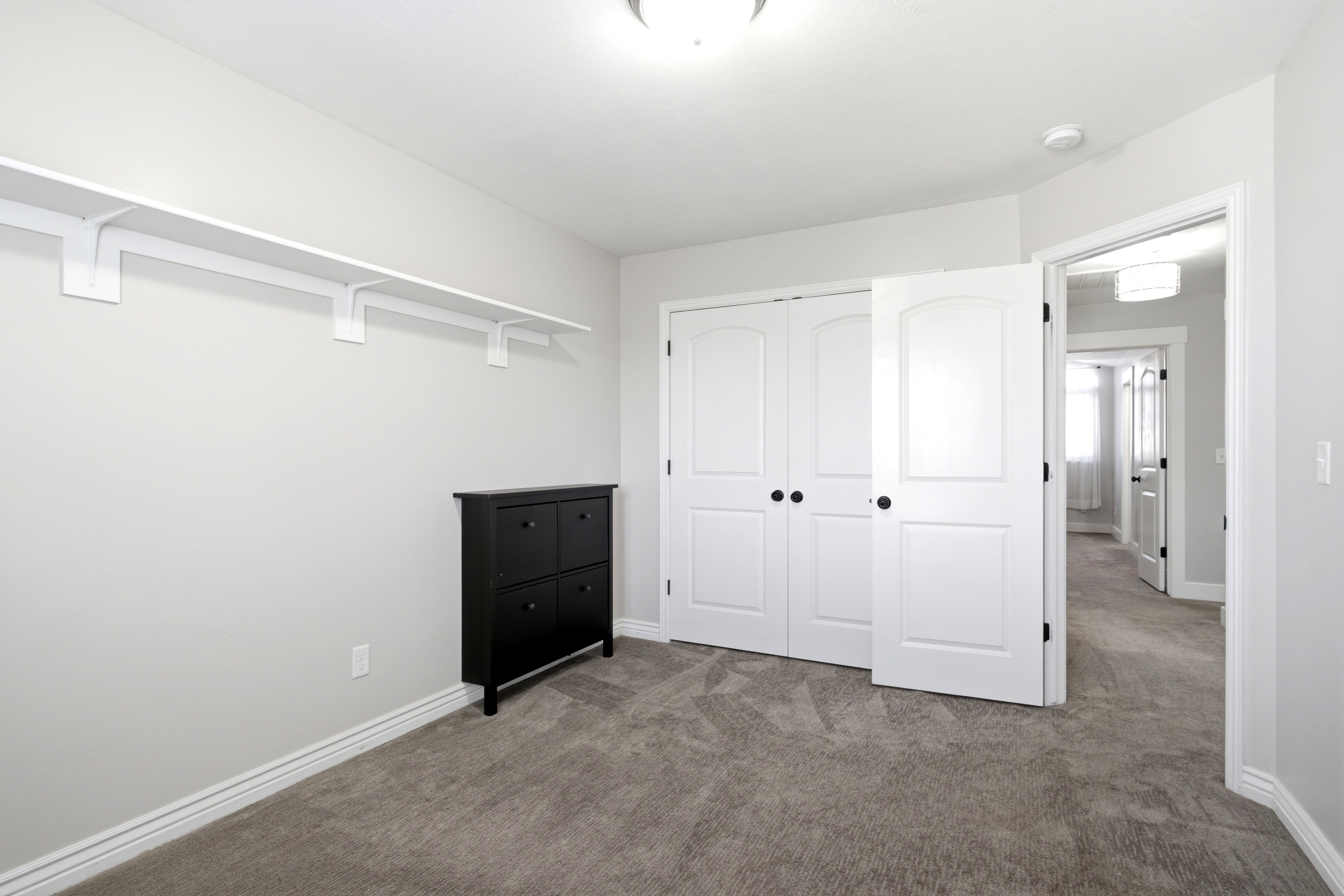 Carpeted interior room featuring light gray walls and white trim