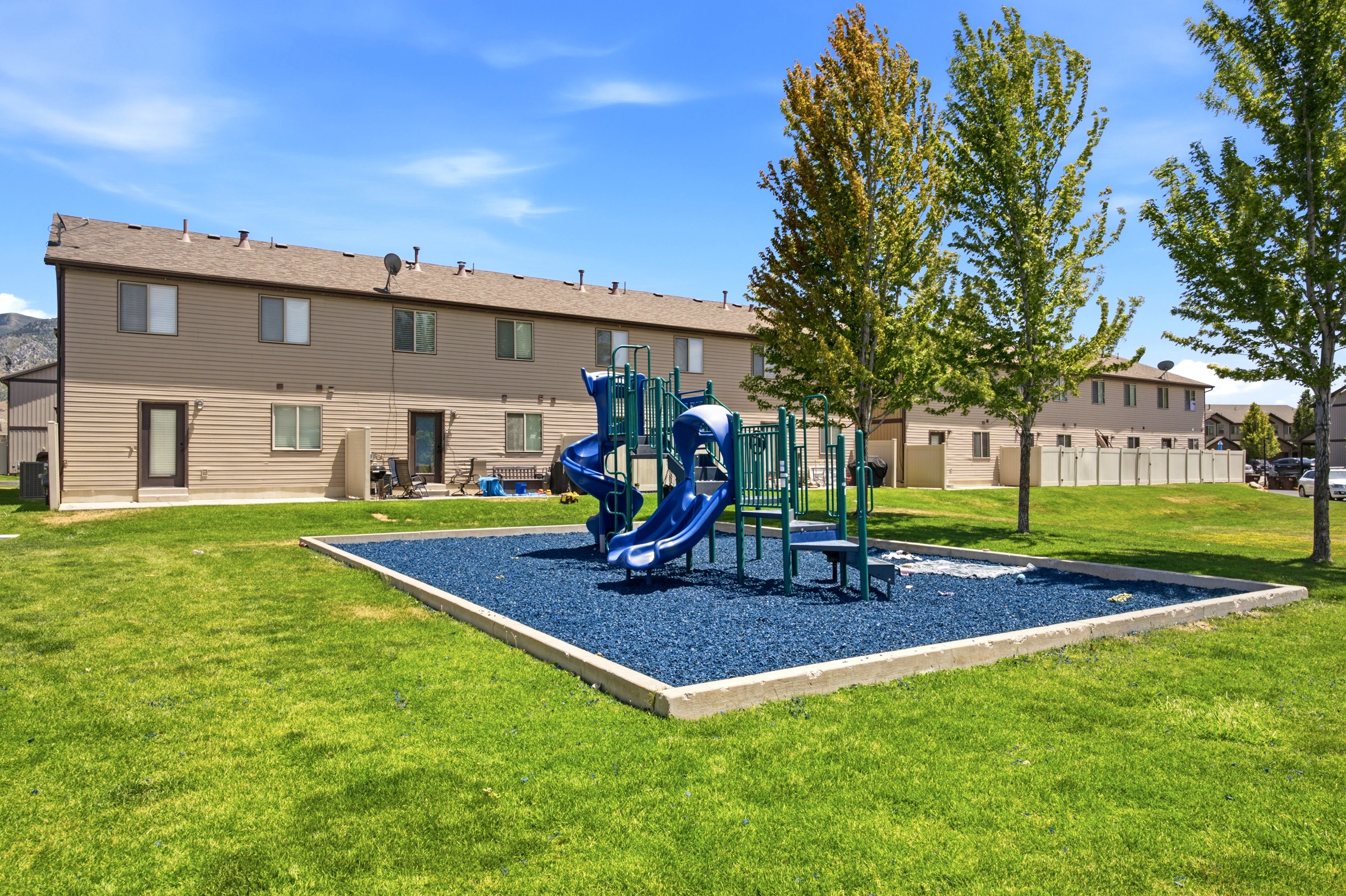 Expansive greenspace featuring a dedicated playground area with blue rubberized surfacing