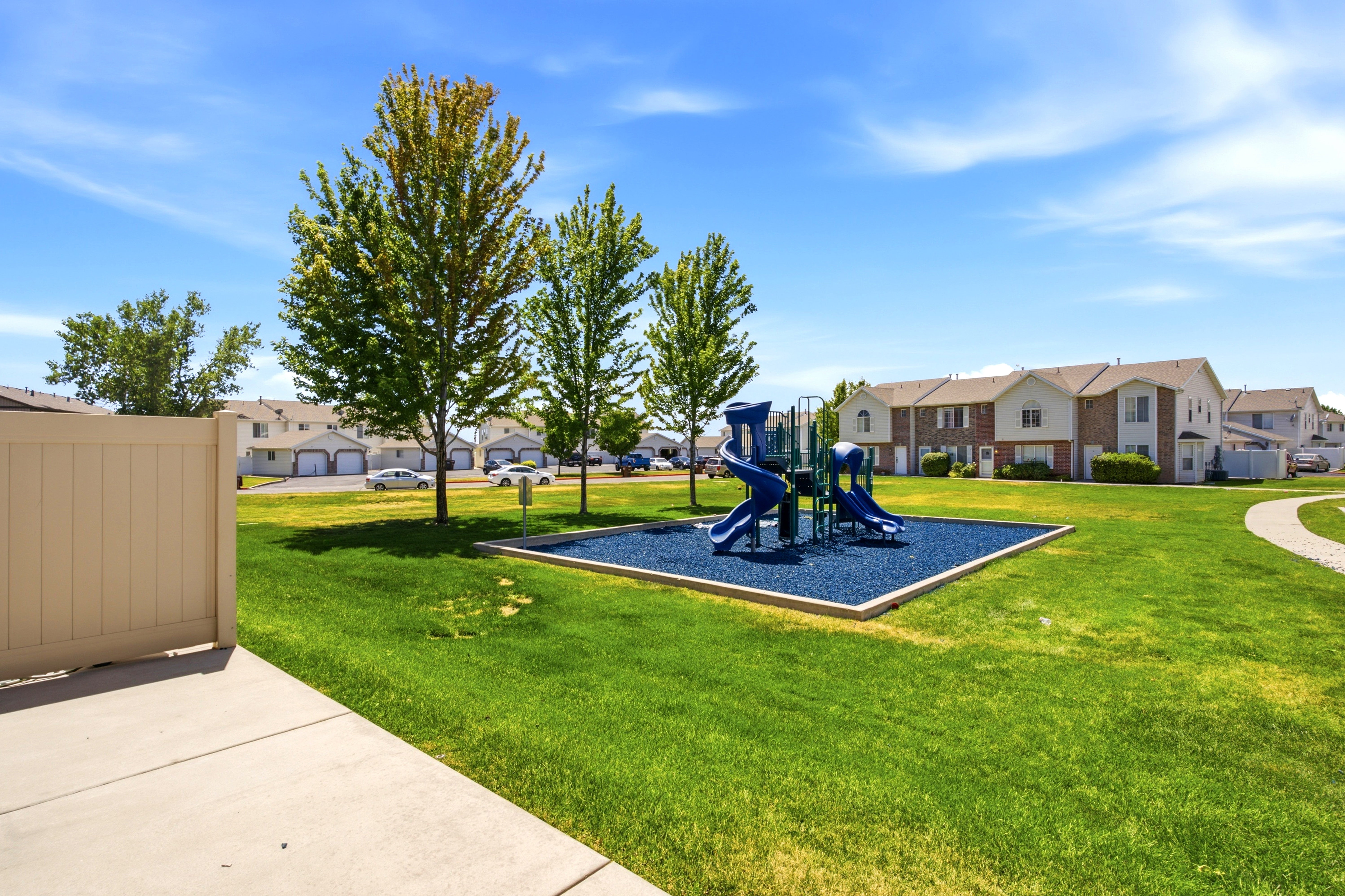 Community playground featuring blue soft-fall surfacing, multiple slides, and climbing structures