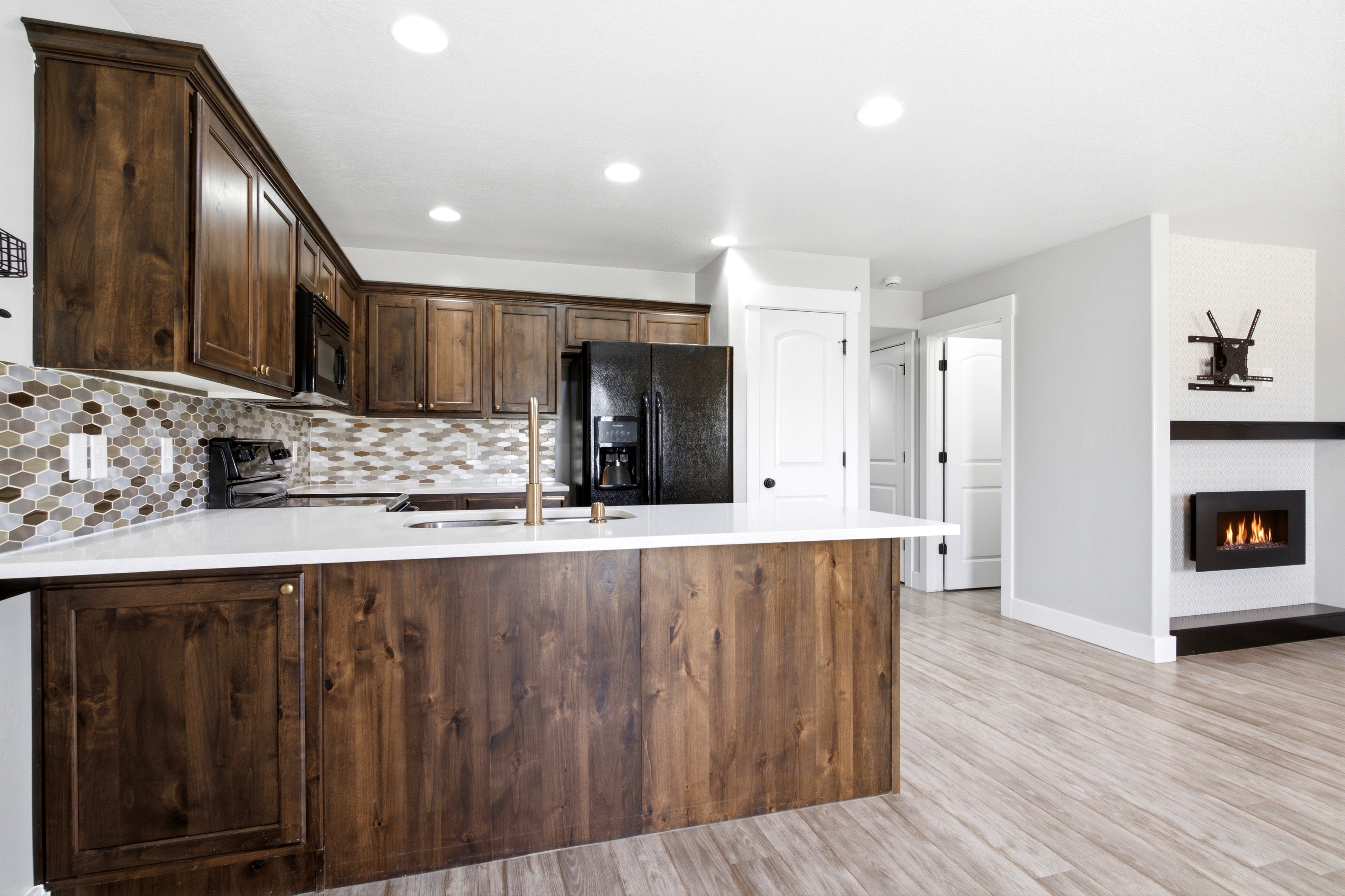 Kitchen featuring dark wood cabinetry, white countertops, and a mosaic tile backsplash