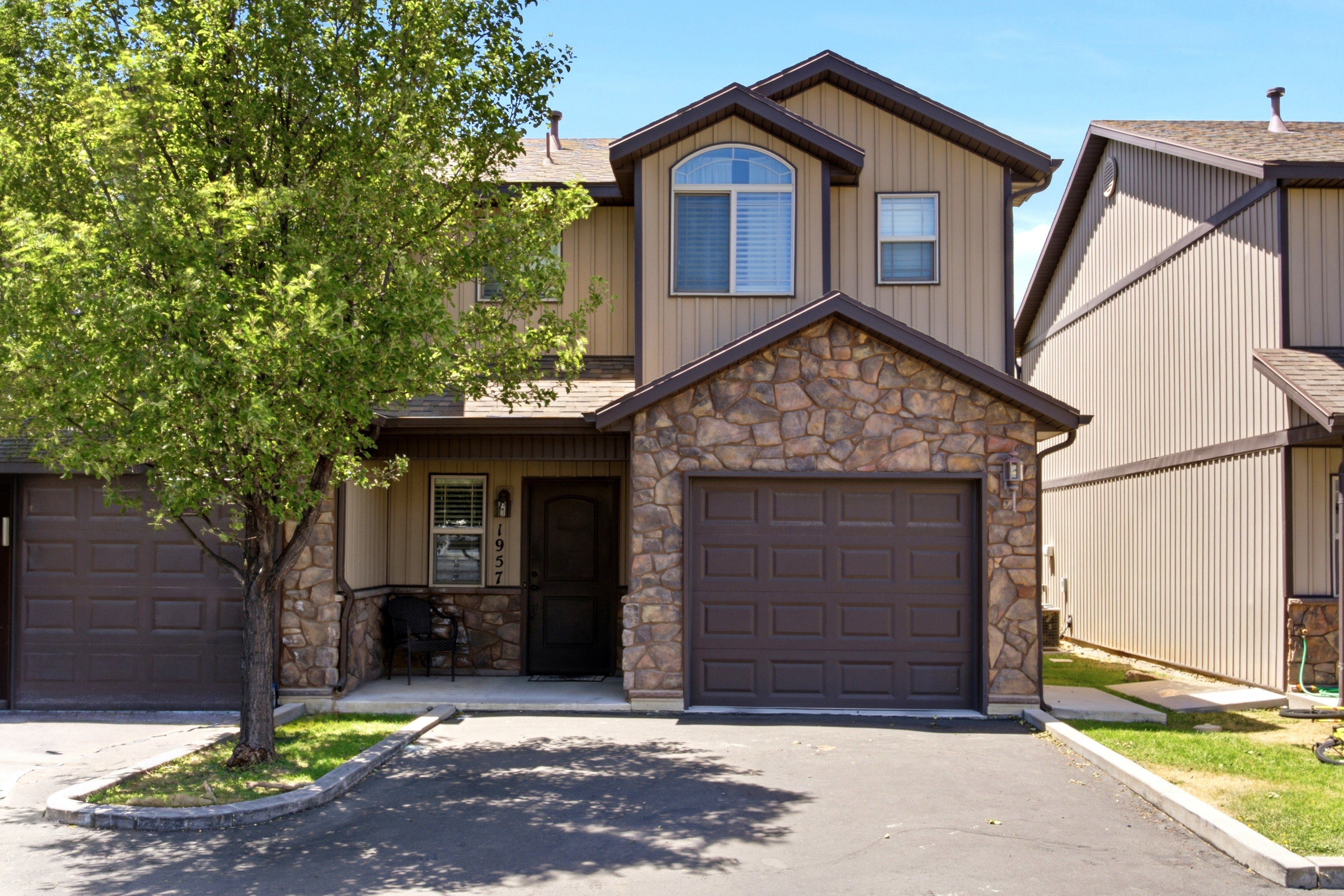 Two-story exterior featuring stone and vertical siding, an arched window, and an attached single-car garage