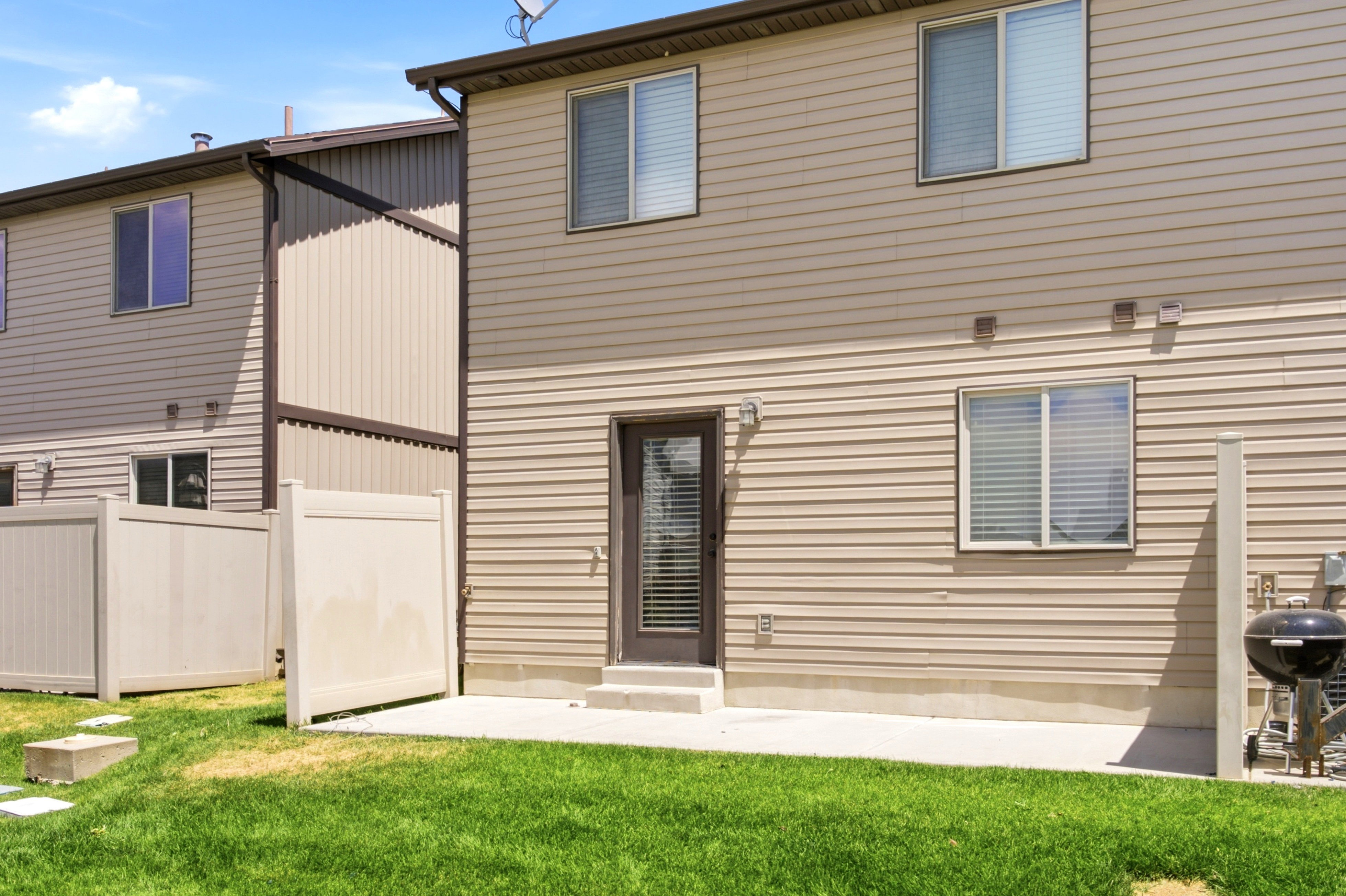 Rear exterior featuring tan horizontal siding and a concrete patio