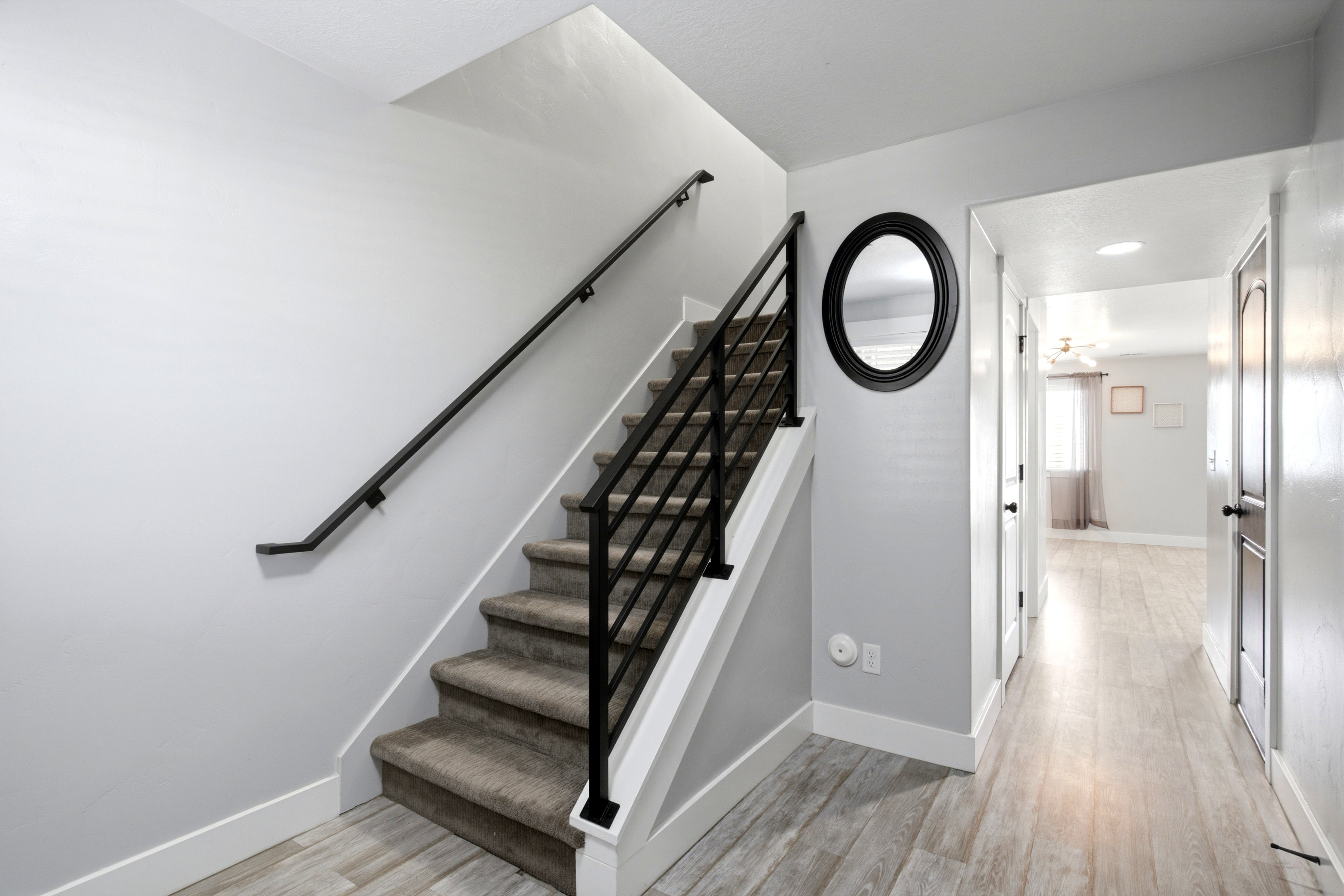 Modern staircase featuring a black metal railing and carpeted treads