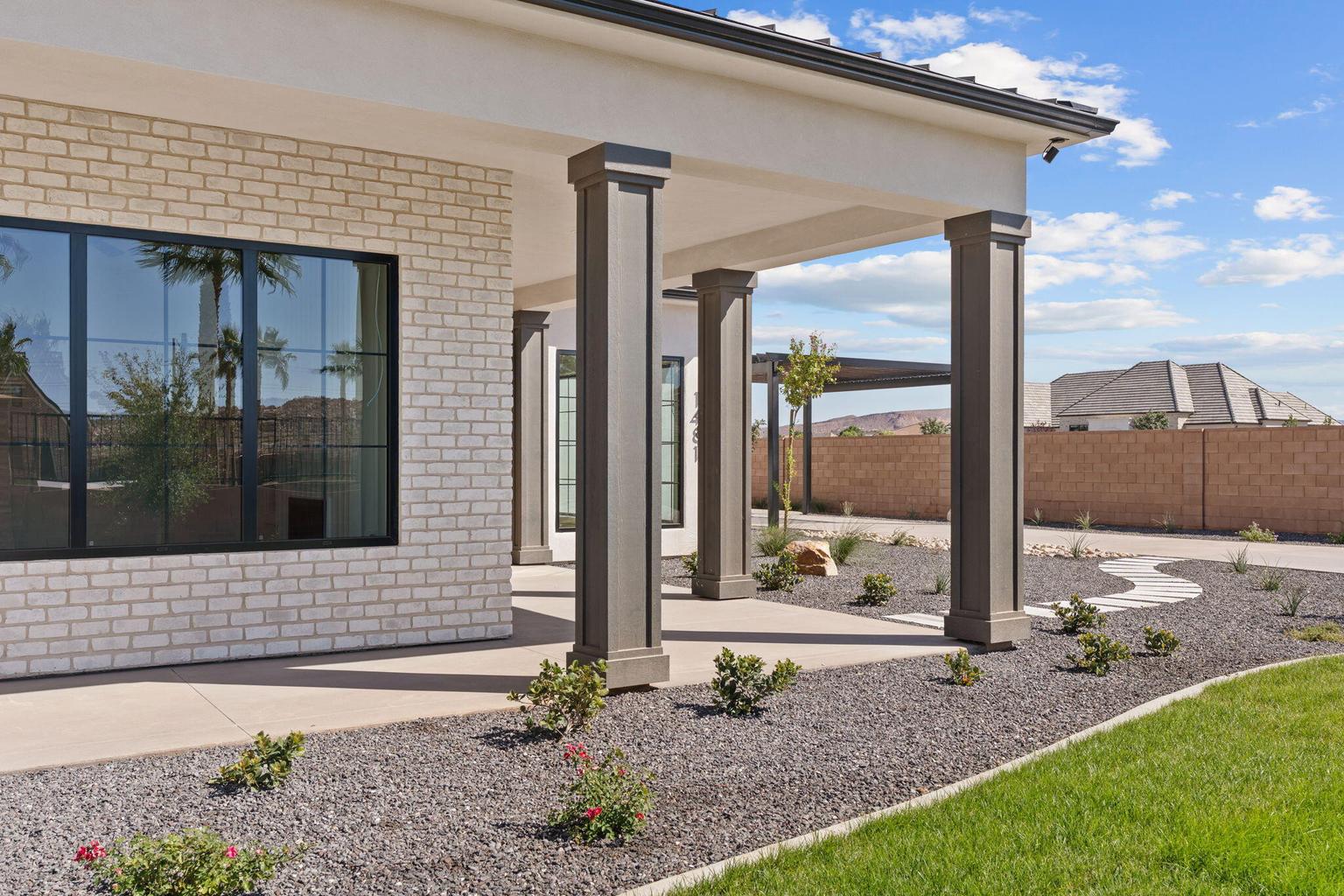 Exterior patio featuring robust columns, light-toned brick facade, and large black-framed windows