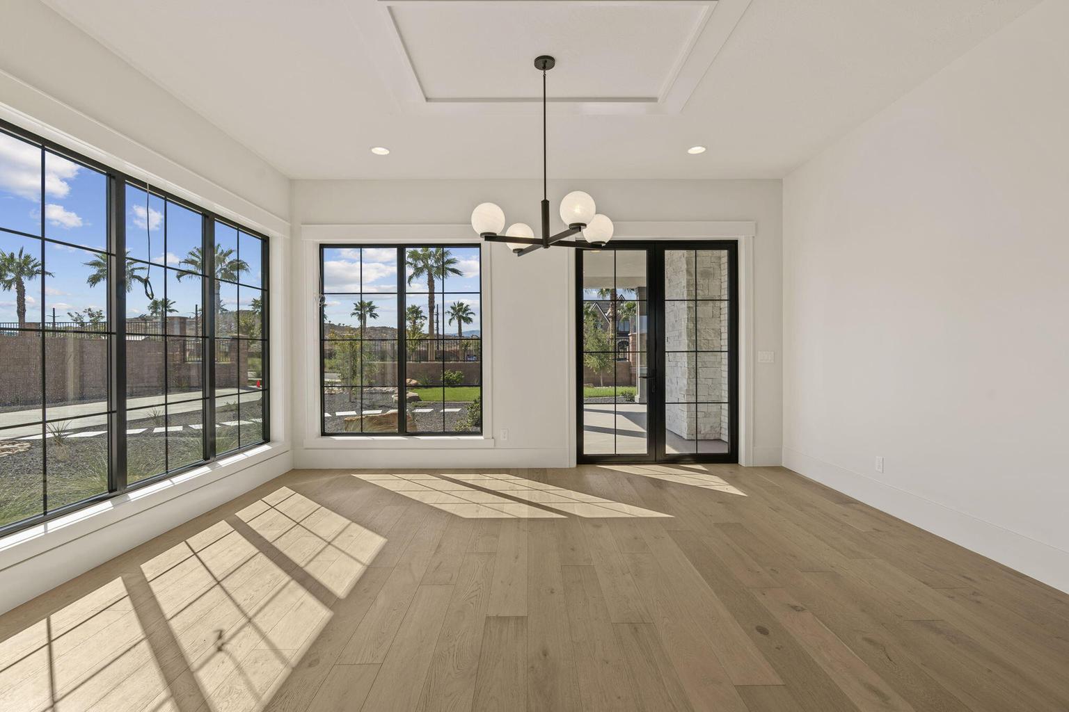 Expansive room featuring light wood-finish flooring, a modern chandelier, and a recessed ceiling panel