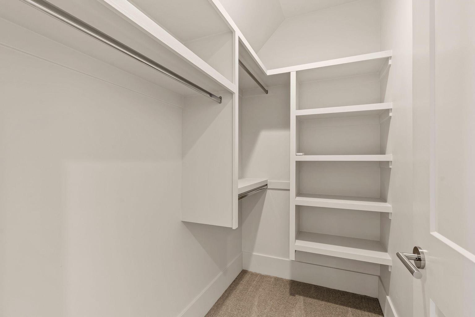 Walk-in closet featuring built-in shelving, multiple hanging rods, and neutral-toned carpeting
