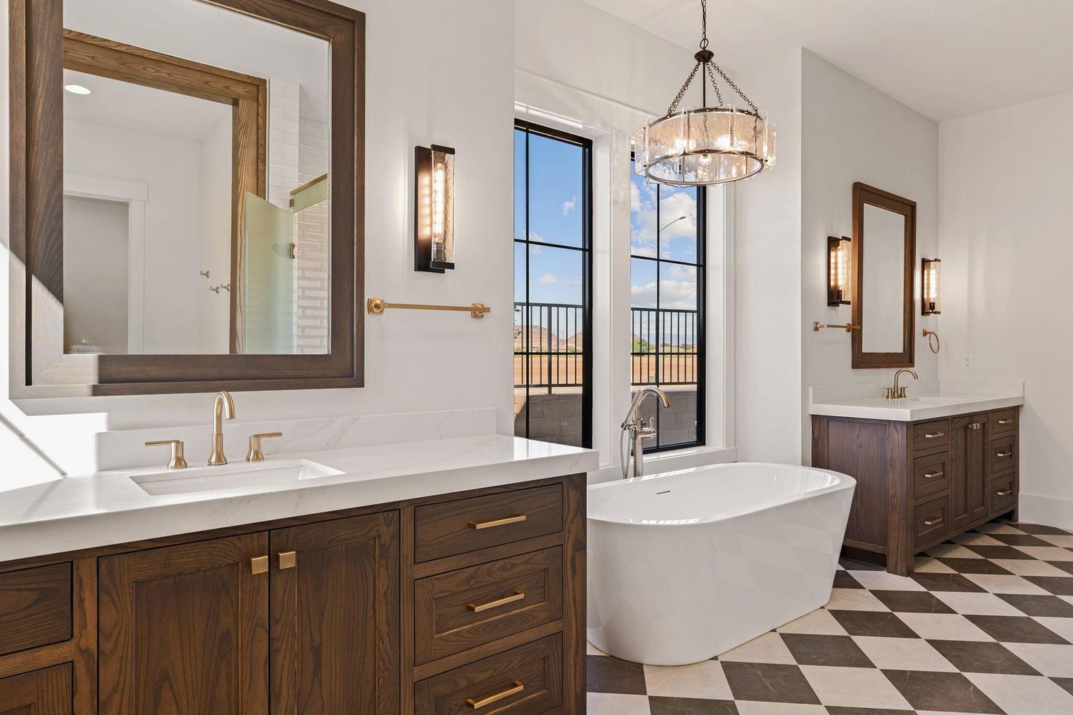 Spacious bathroom featuring a freestanding soaking tub, dual wood-finish vanities with white countertops, checkerboard floor tiling, and a large window with black framing