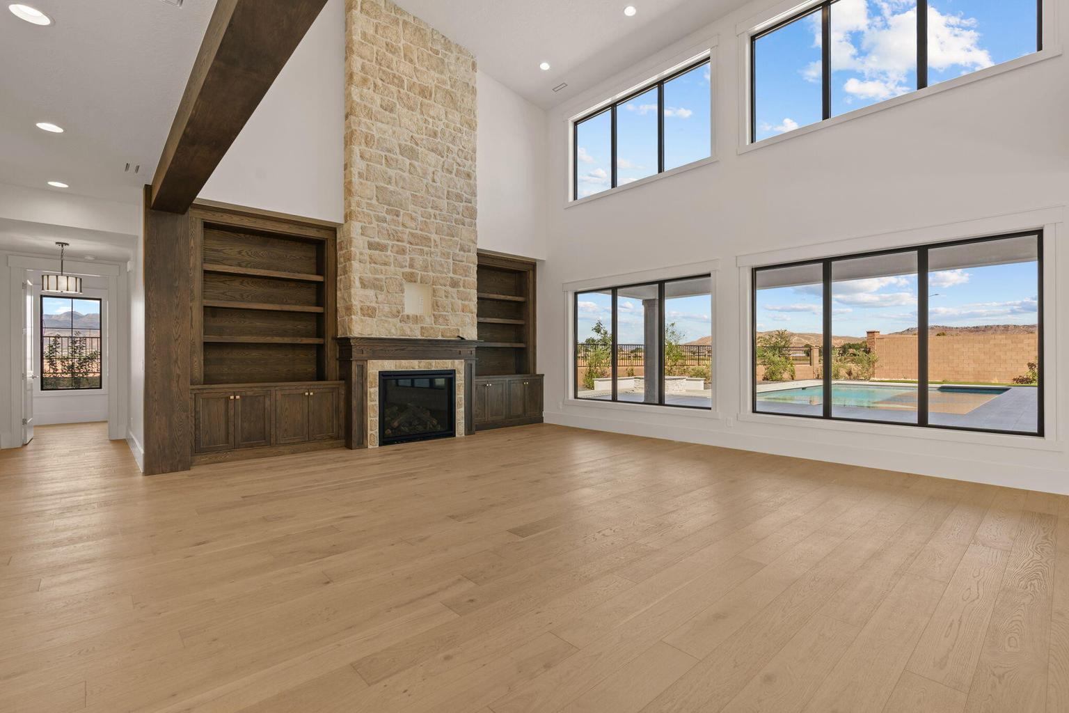 Open-concept living space featuring high ceilings, wood-finish flooring, and a stone fireplace with a wood mantle