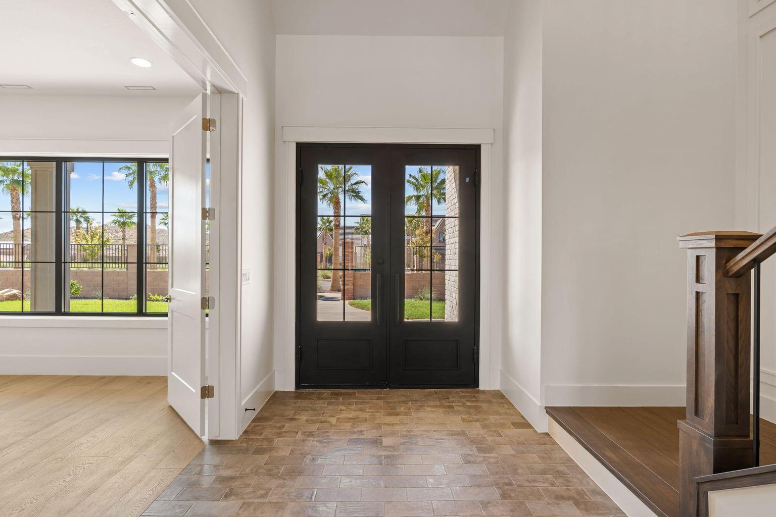 Entryway featuring a dark wood double door with glass lites, tile flooring, and white trim