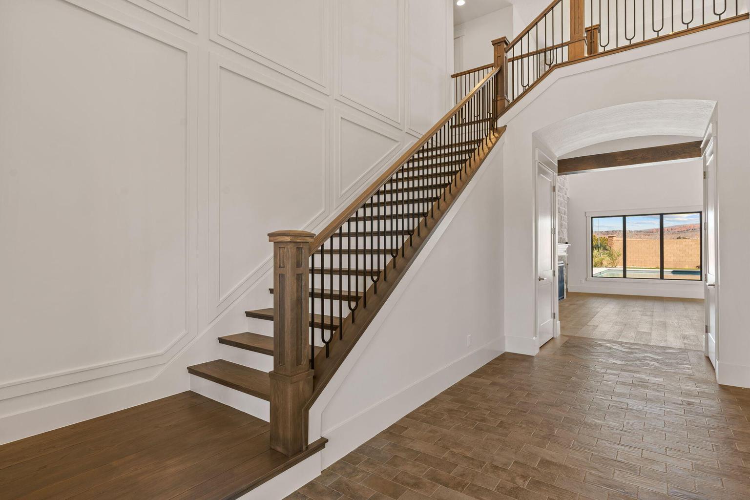 Grand staircase featuring wood treads, wood newel posts, and decorative metal balusters