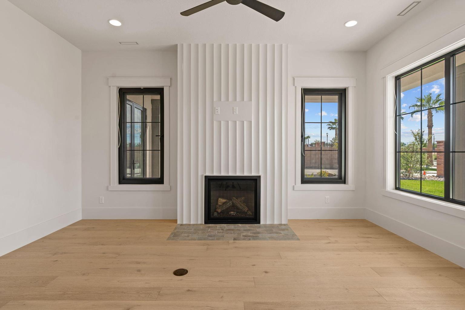 Light wood-finish flooring complements the white walls and modern fireplace with a textured surround and hearth