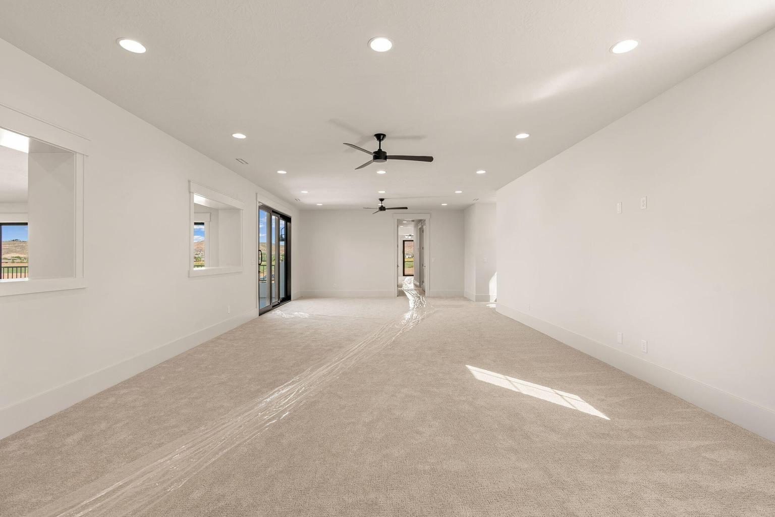 Spacious room featuring light-colored carpet flooring, recessed lighting, and dual ceiling fans