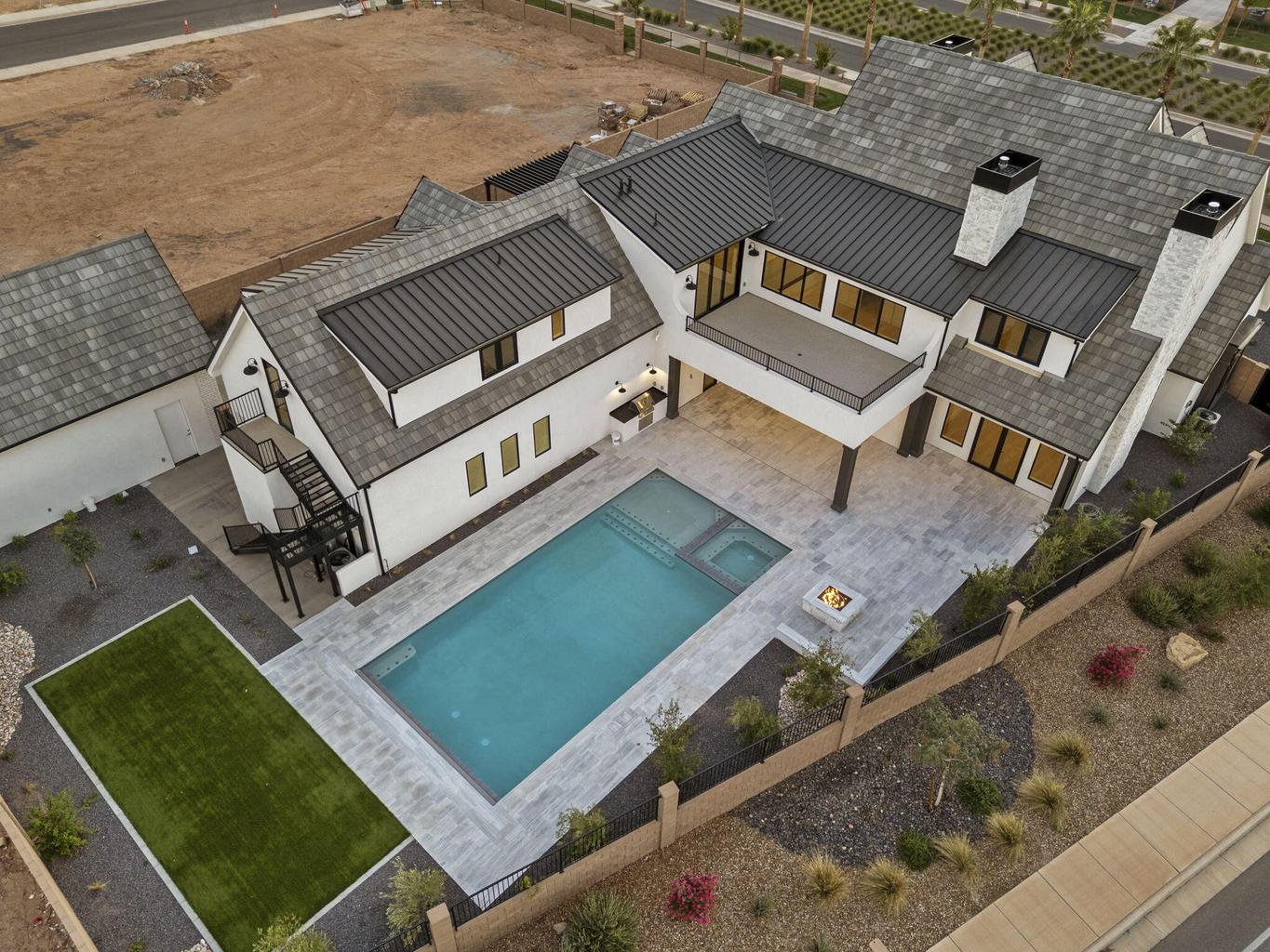 Modern farmhouse-style residence with a dark metal roof and white stucco facade