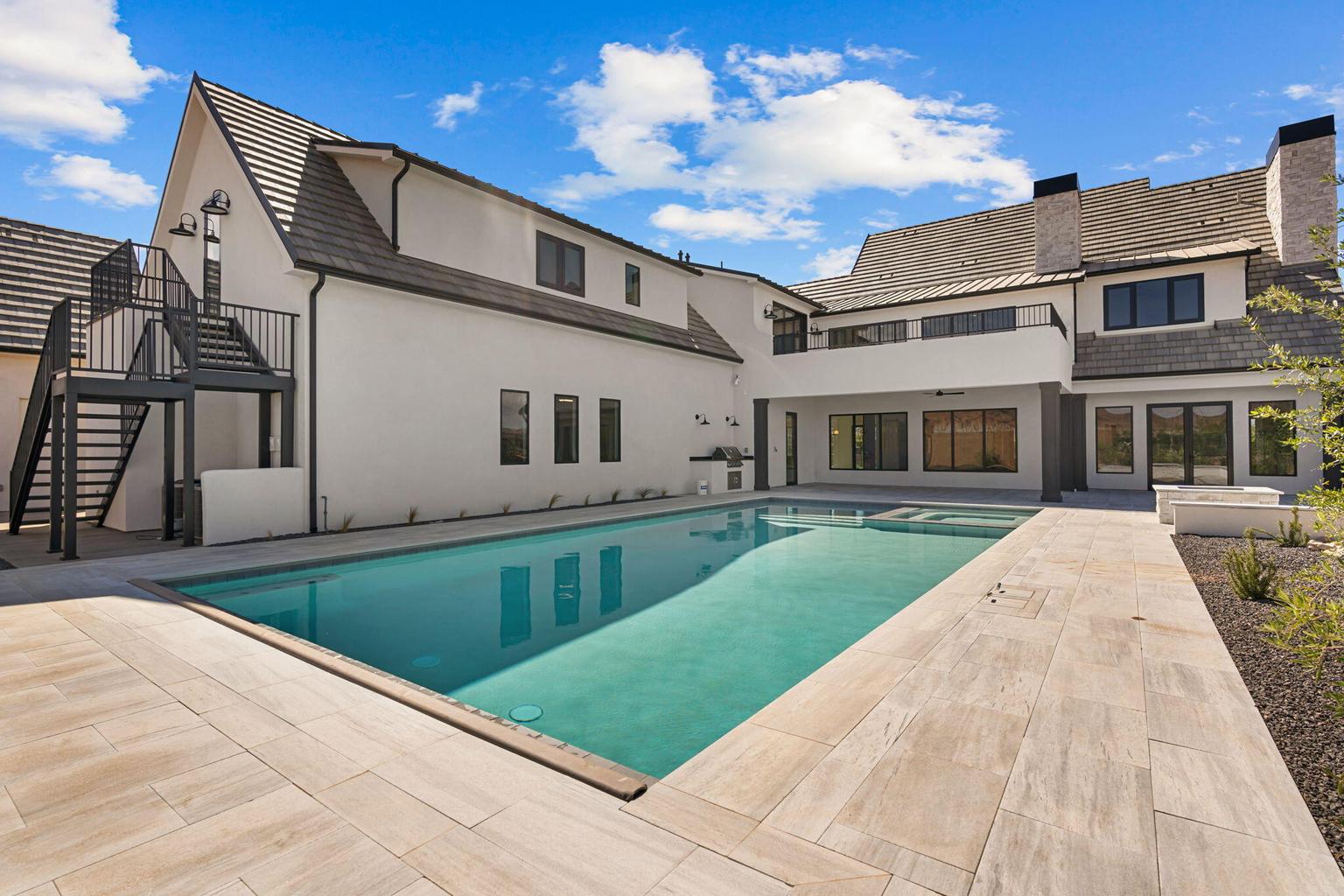 Expansive backyard featuring a rectangular swimming pool with integrated spa and light-toned tile surround