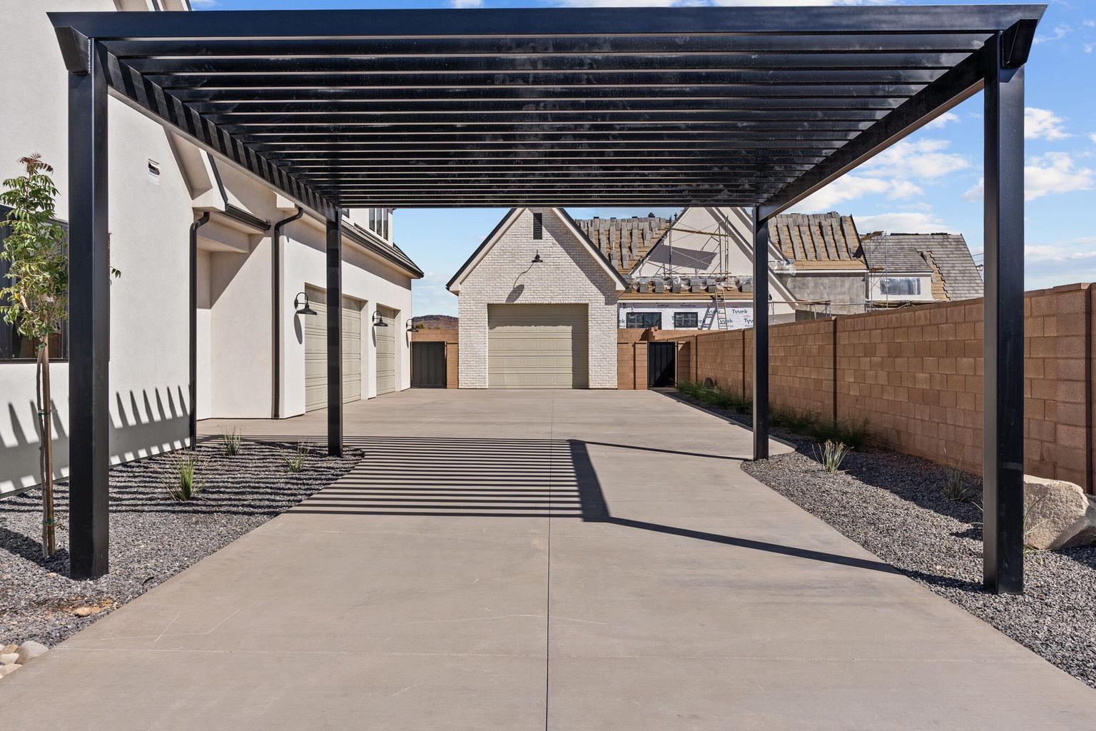Expansive concrete driveway featuring a contemporary black metal pergola
