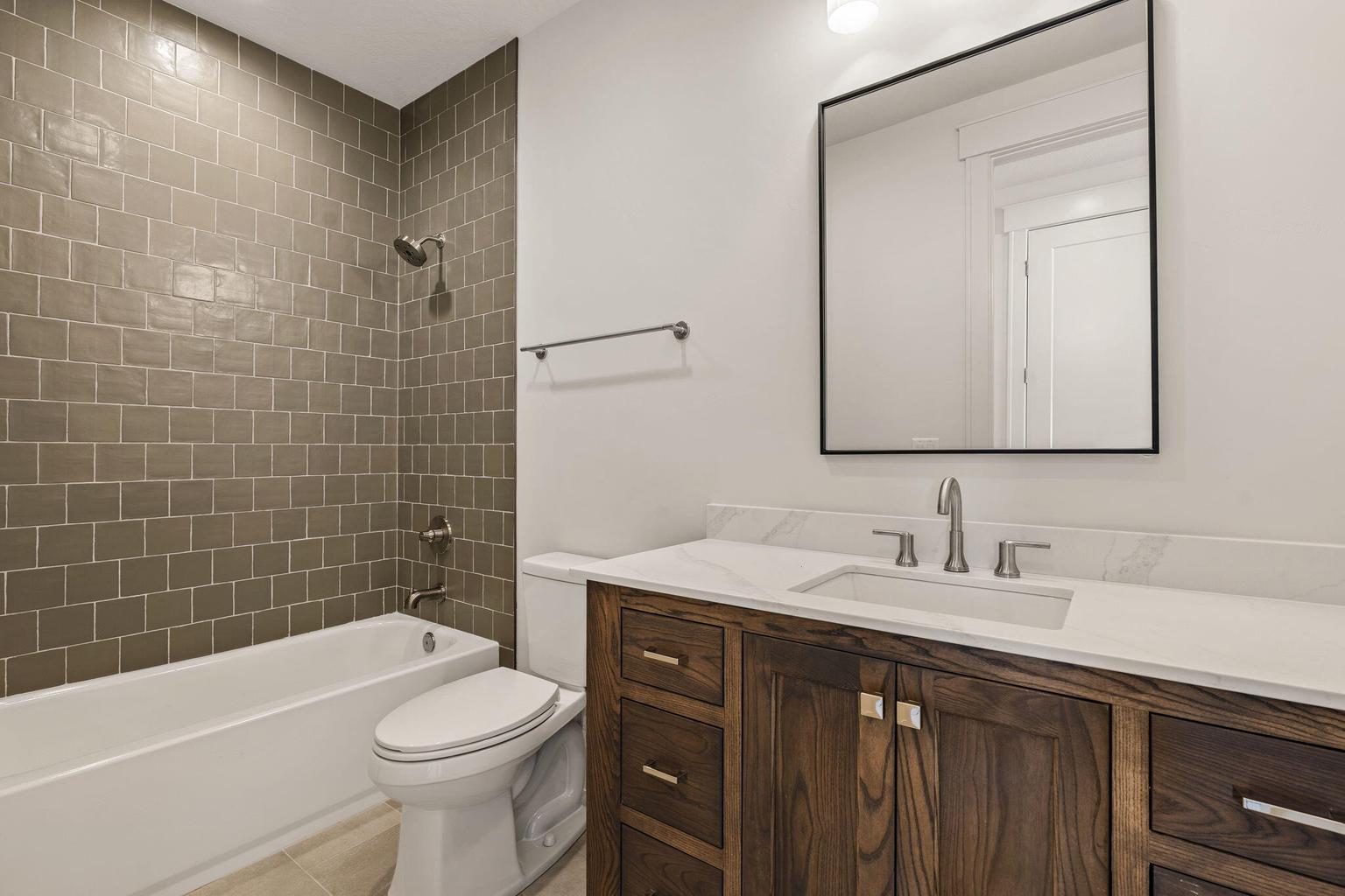 Bathroom vanity with a white countertop and undermount sink, complemented by a wood-finish cabinet