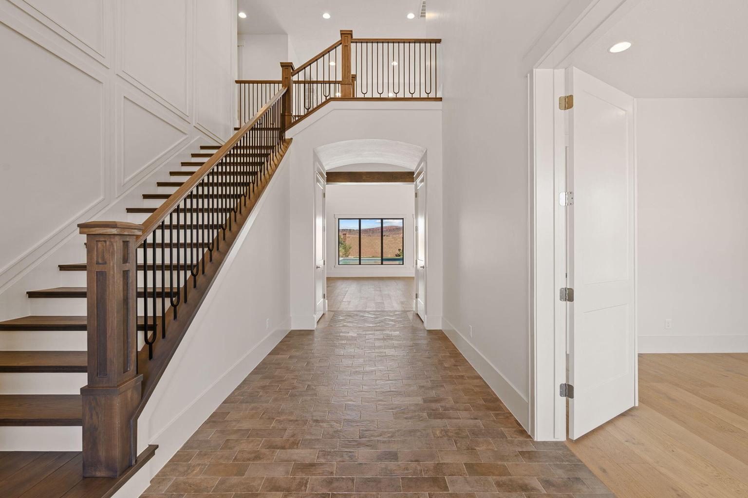 Grand entryway featuring a prominent staircase with dark wood-finish treads, a contrasting white riser, and an ornate wrought iron baluster