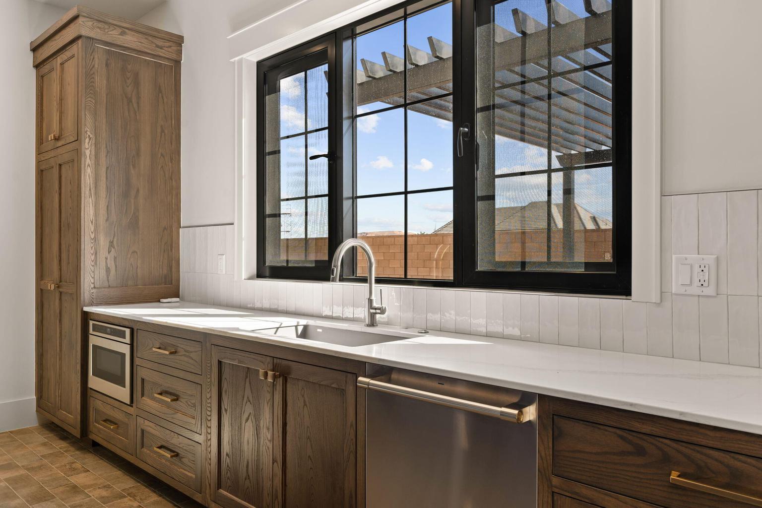 Kitchen area featuring a prominent black-framed window, white subway tile backsplash, and light-colored countertops