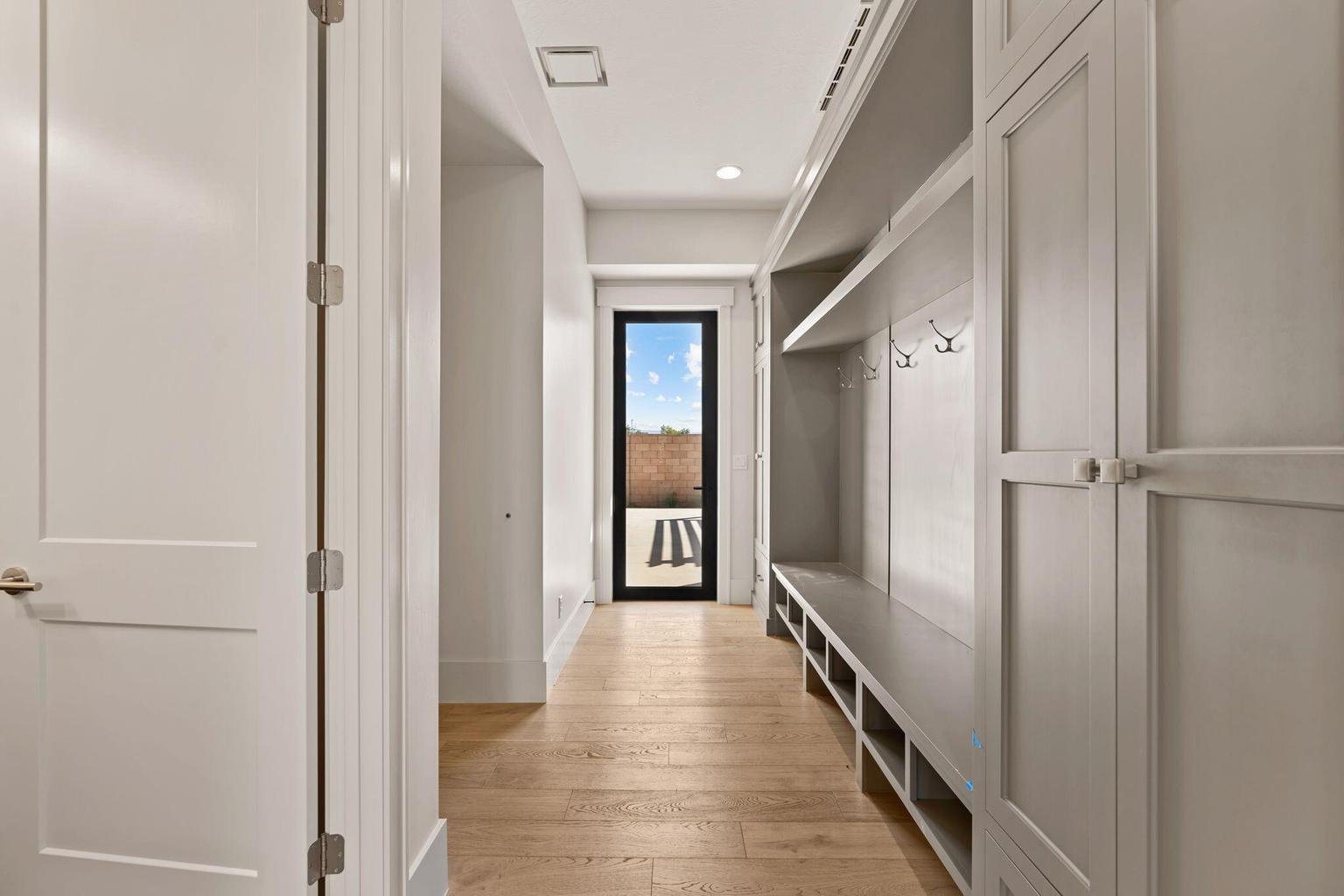 Hallway featuring wood-finish flooring, recessed lighting, and a built-in mudroom bench with storage cubbies and coat hooks