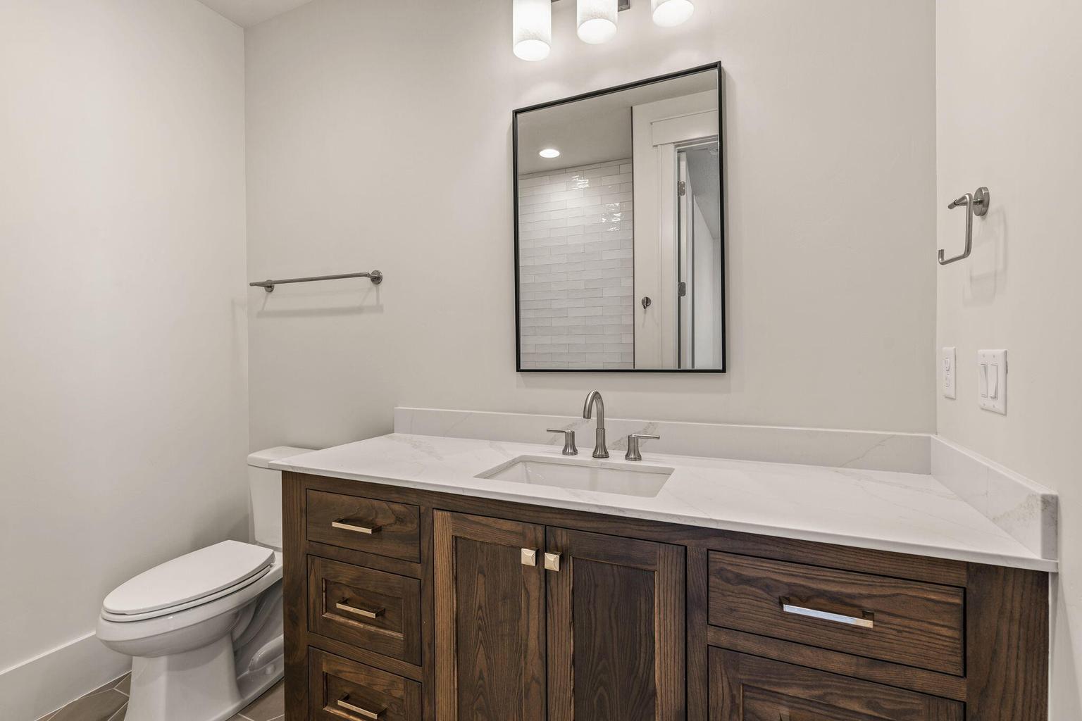 Bathroom featuring a dark wood-finish vanity with an integrated sink, a white countertop, and contemporary brushed nickel hardware