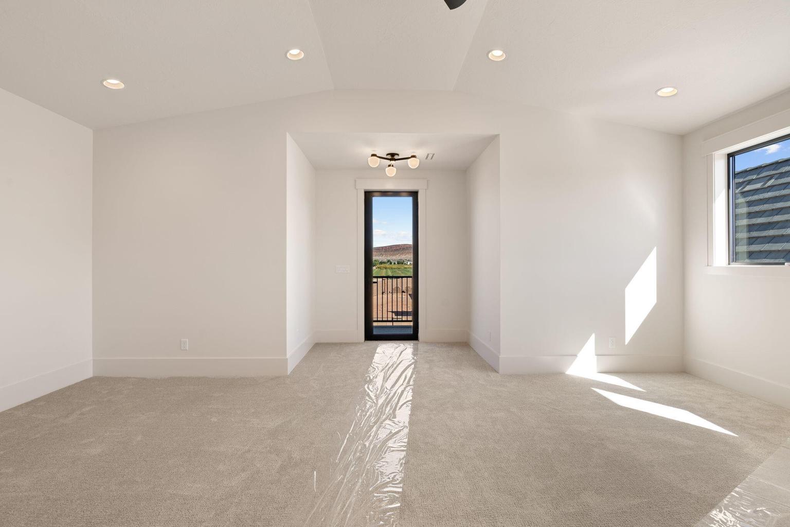 Carpeted room featuring a ceiling fan, recessed lighting, and a full-height glass door opening to a balcony with a wrought iron railing